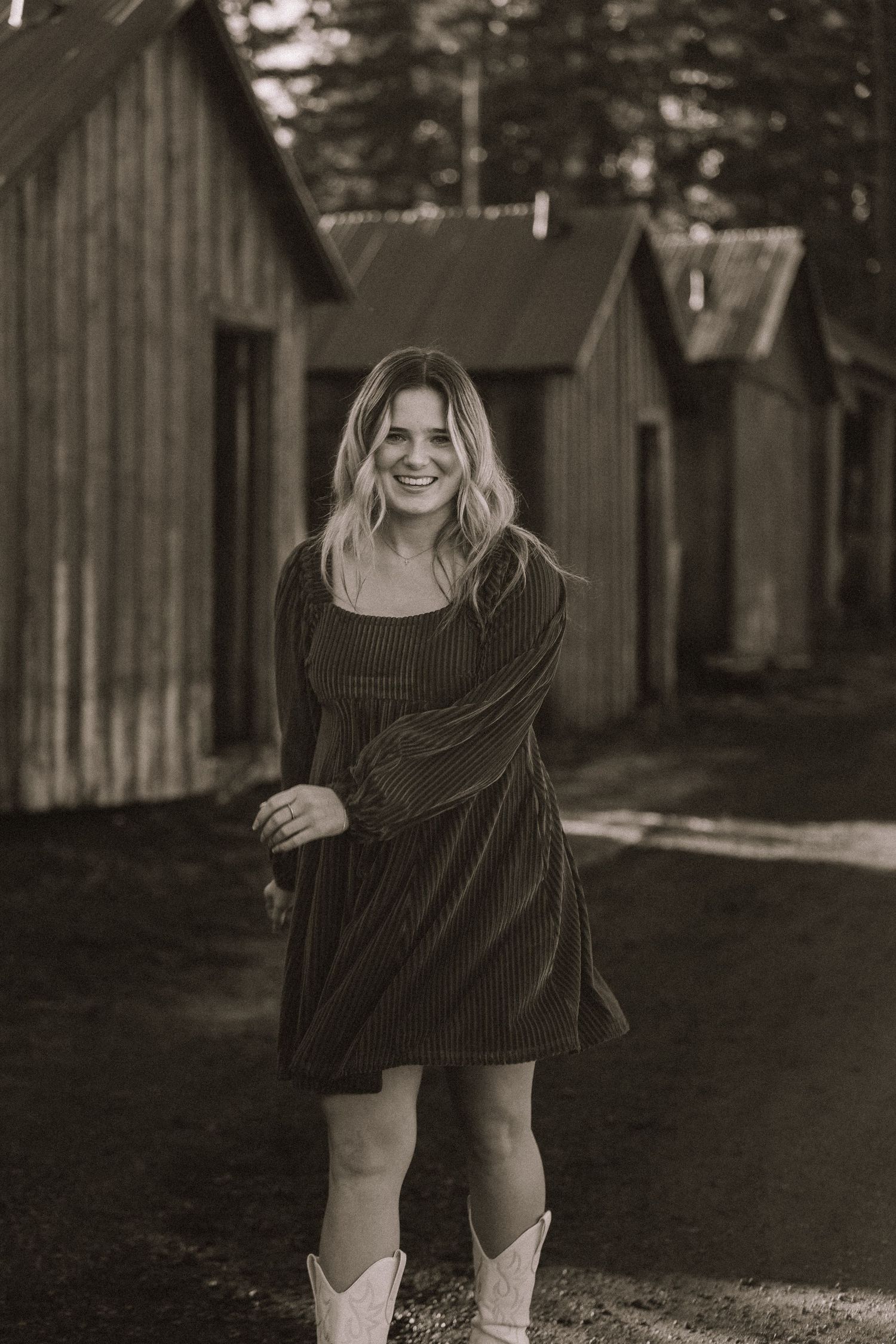 A playful photoshoot in front of rustic wooden buildings at dusk.