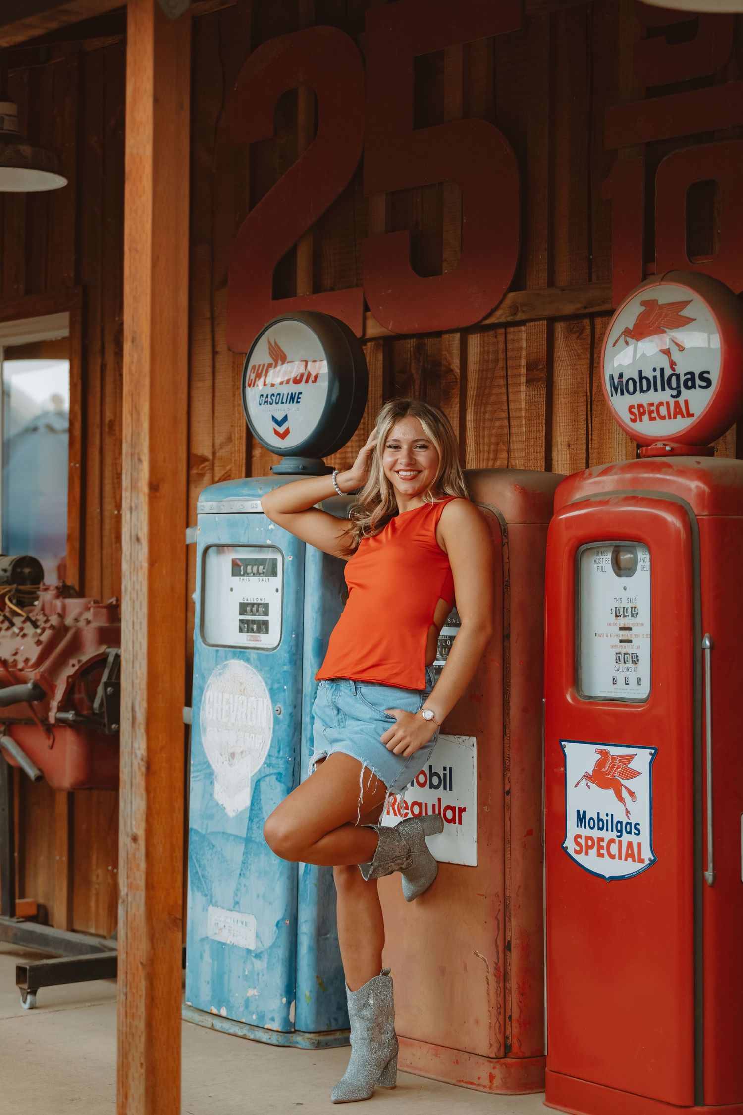 Orange tank top and denim shorts styled against vintage Mobilgas station backdrop.