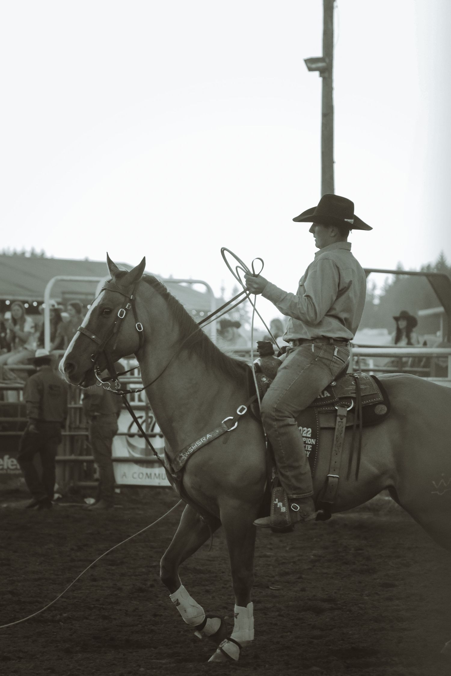 Vintage black and white photo of riders preparing their horses at a rodeo event.