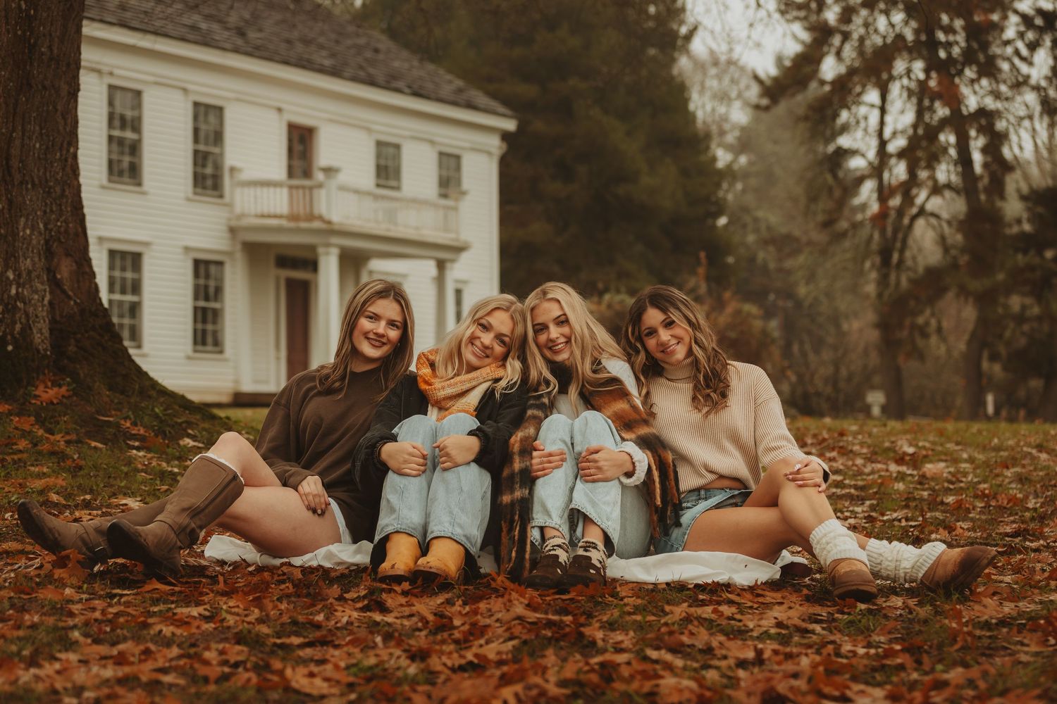 A series of cozy autumn family photos showing people relaxing on fallen leaves near a white house in warm lighting.