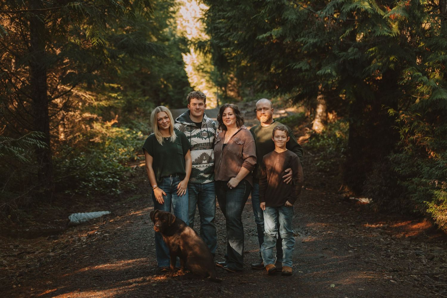 A group walking together on a wooded path during golden hour with sunlight filtering through autumn trees.