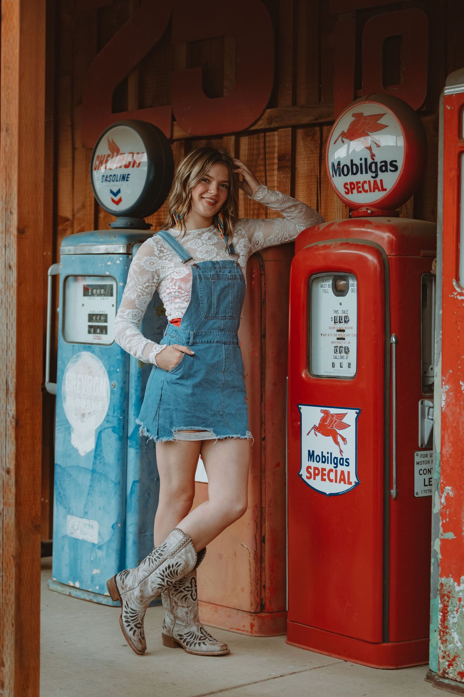 Artistic portrait session against vintage gas station equipment and wooden architecture.
