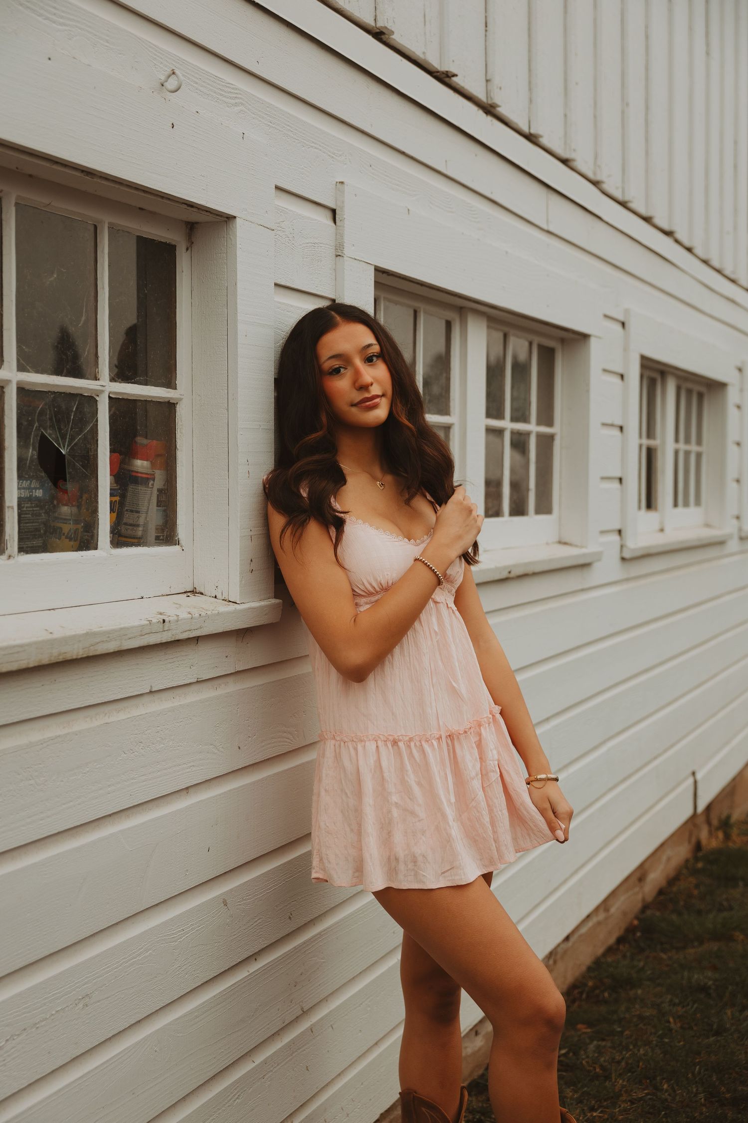 A fashion photoshoot against a white building exterior featuring a pink summer dress.