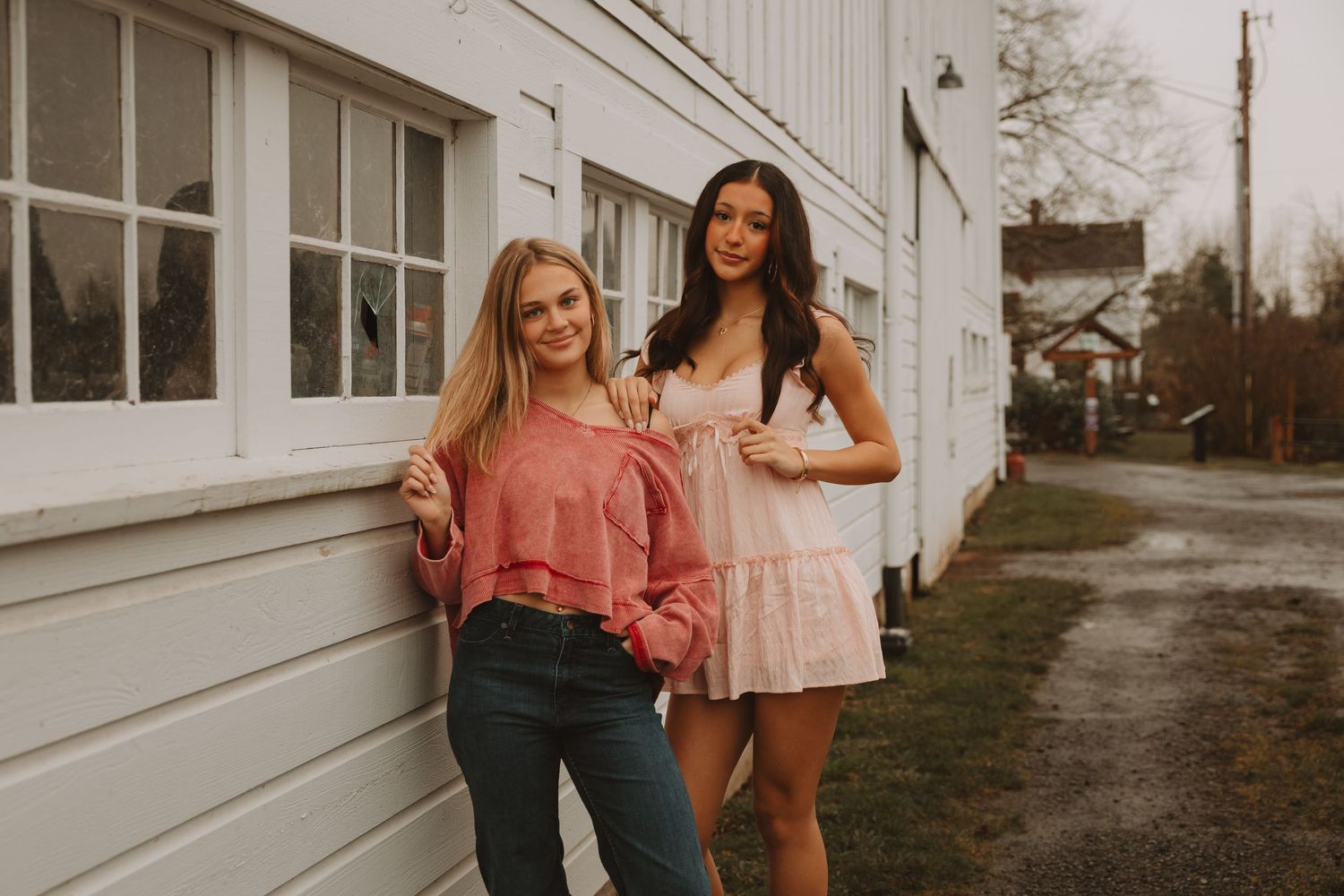 Friends posing casually against a white building exterior in warm afternoon light.