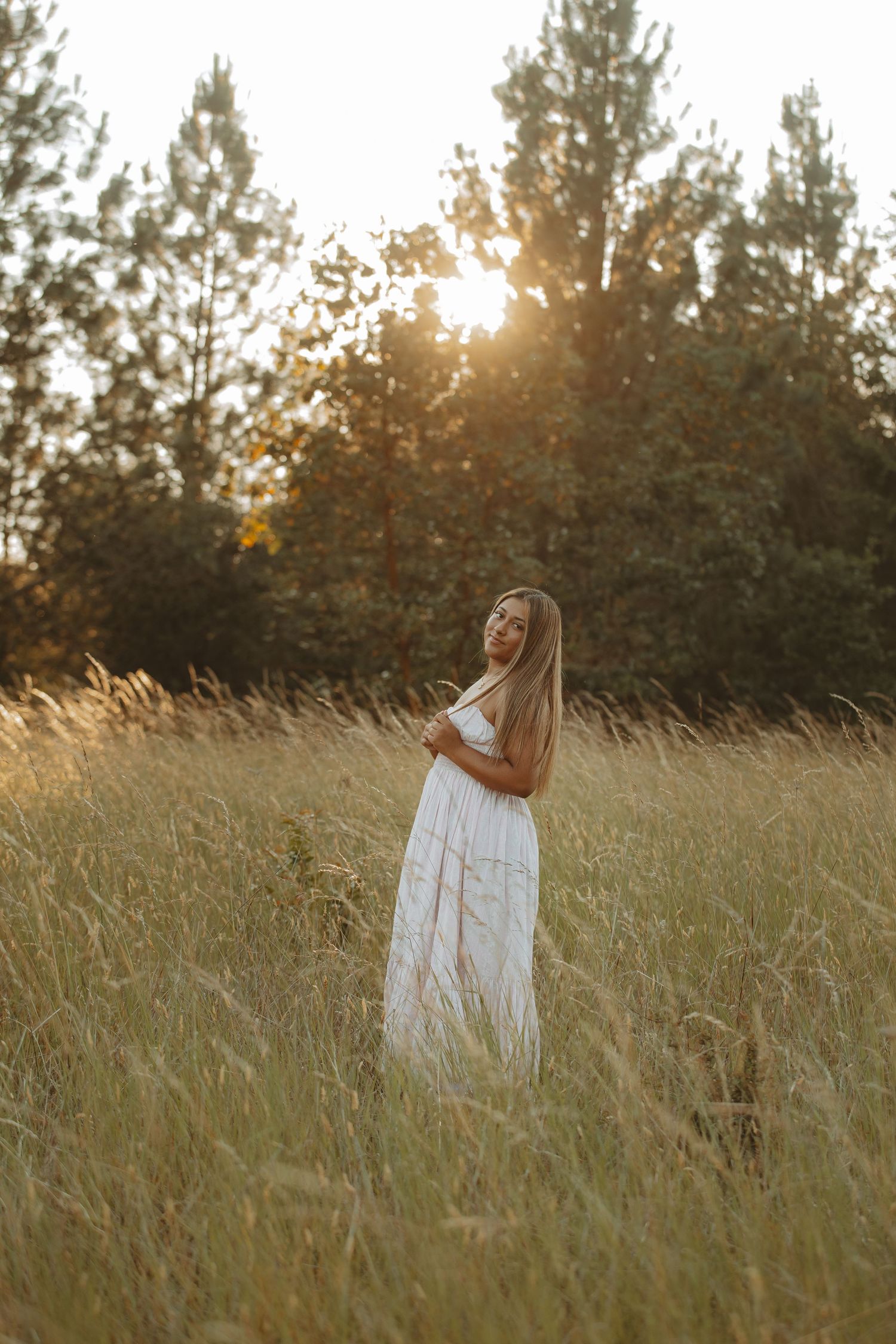 White dress contrasts beautifully with golden grass during sunset in a meadow.