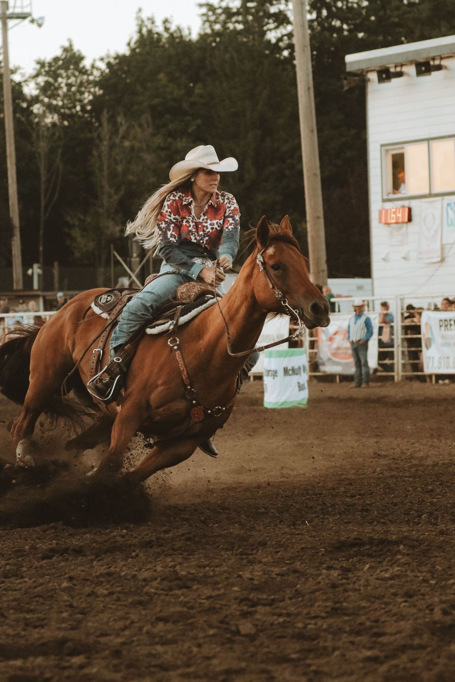 Barrel racing competition with riders on horses racing through arena at high speed.