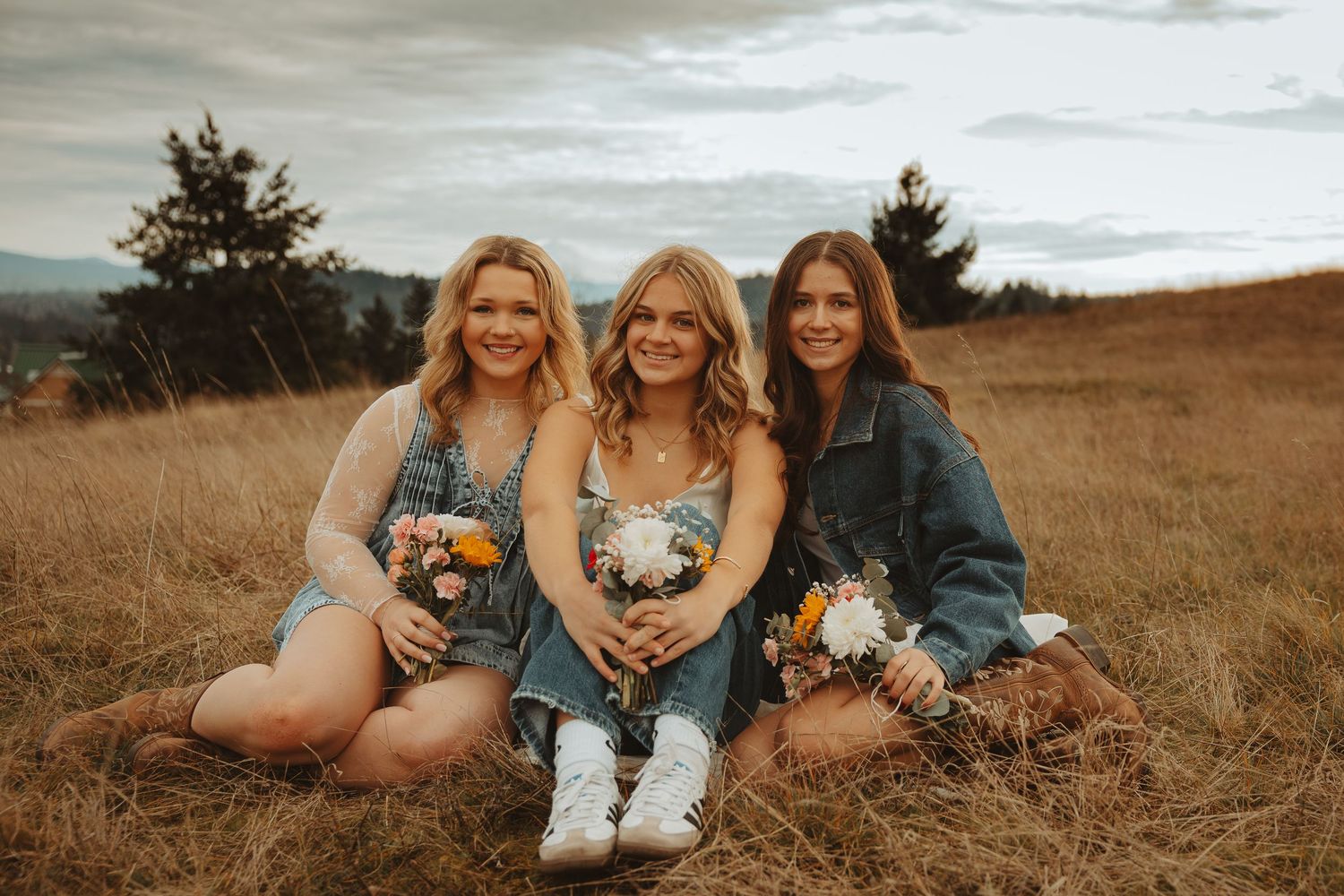 A group of friends in blue dresses laying in a golden field during sunset creating a joyful outdoor photo series.
