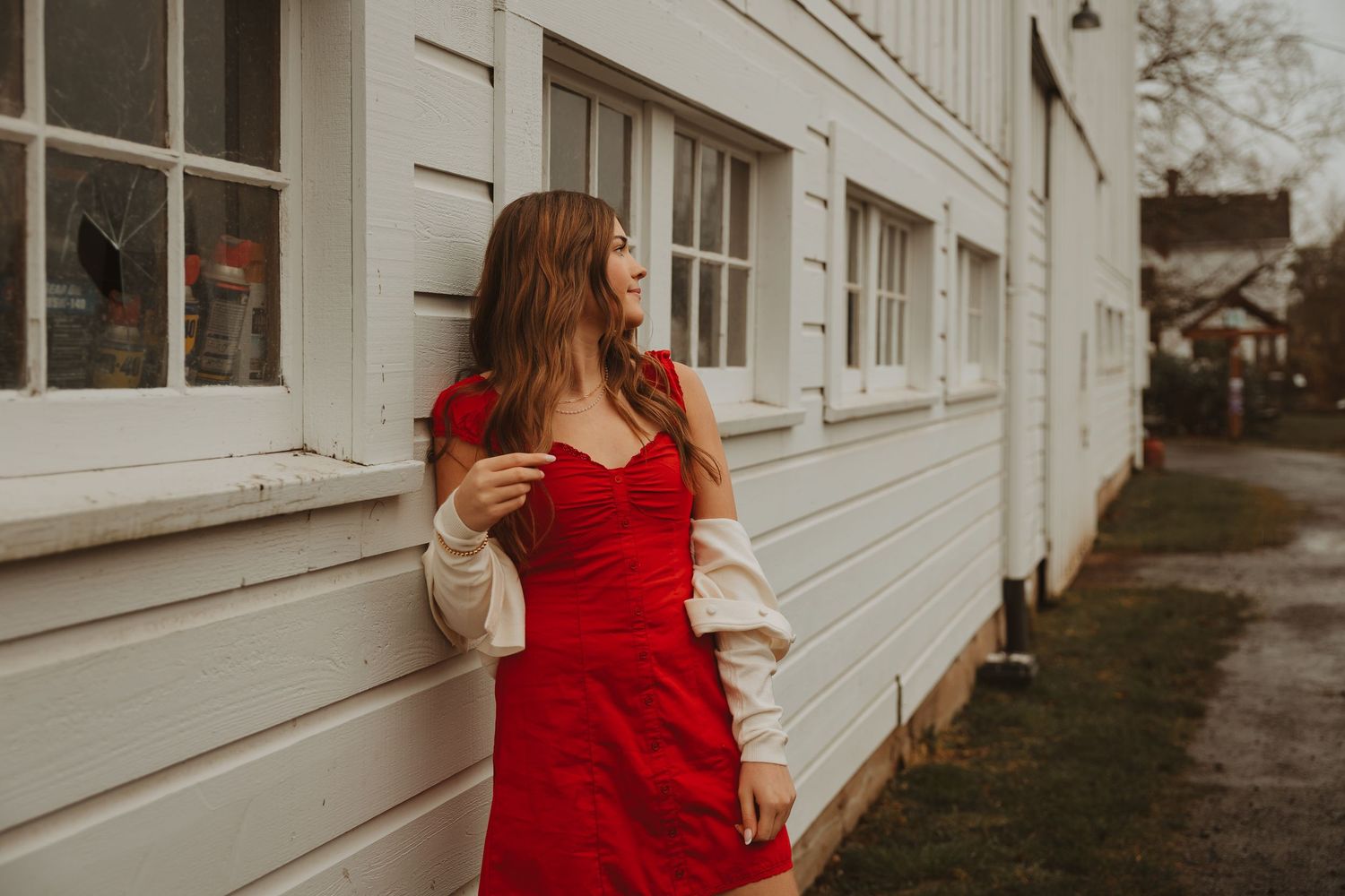 A woman in a flowing red dress twirls and dances against a white building exterior.