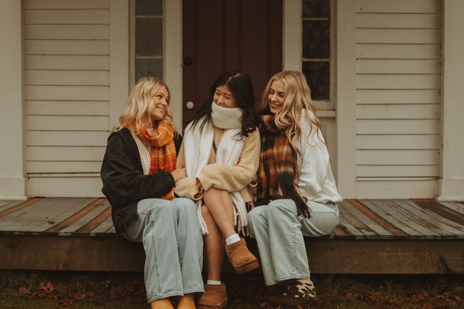 A group sits together on a wooden porch, sharing laughter and conversation in casual attire.