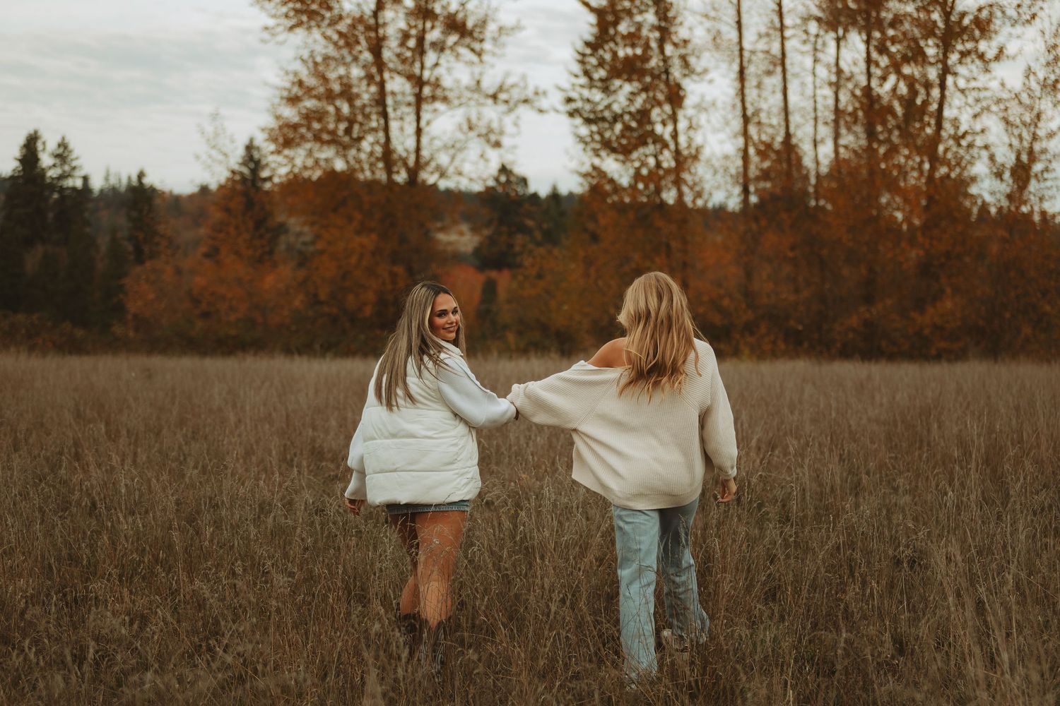 Two people in casual attire walk together through a golden autumn field.