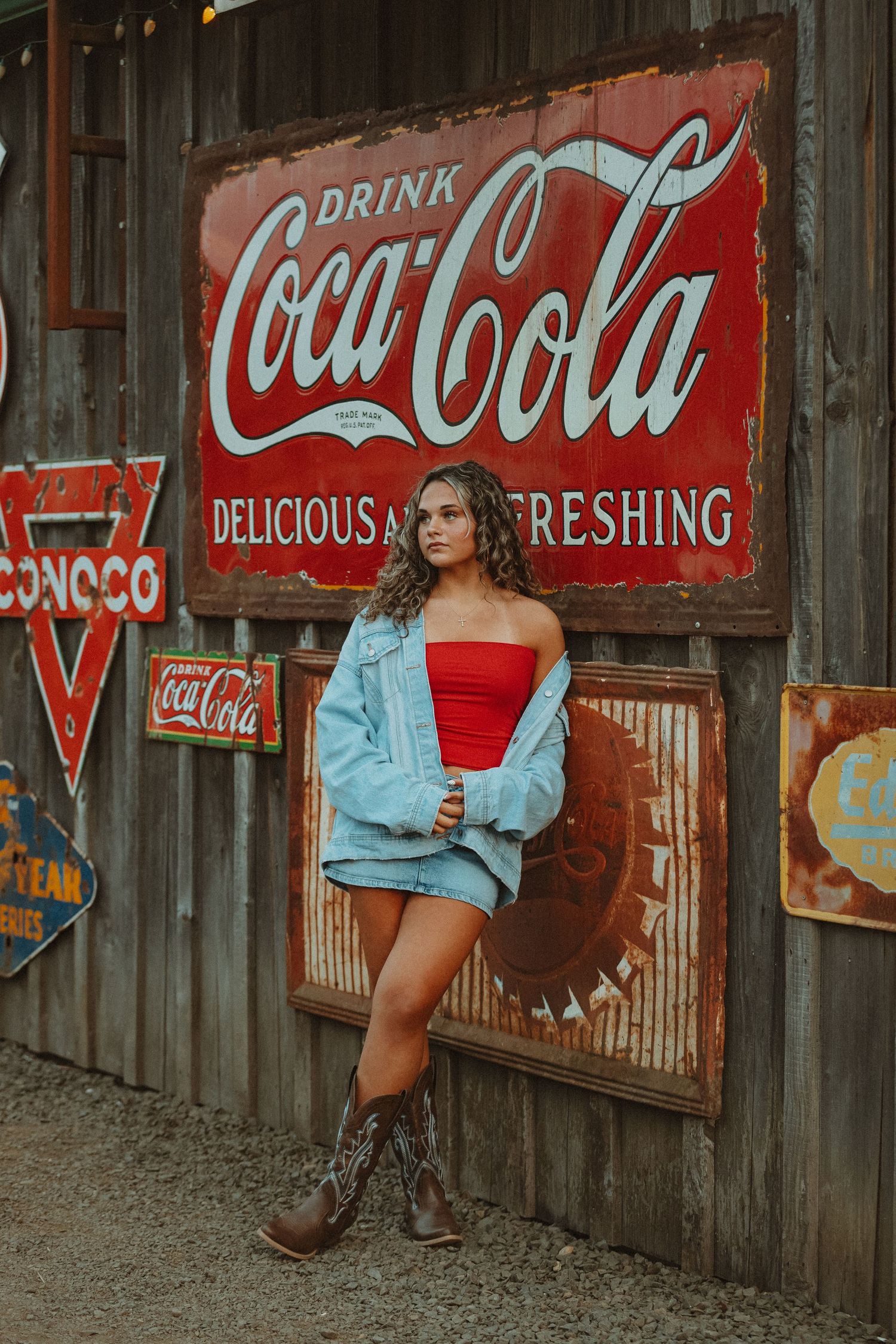 Retro photoshoot against vintage Coca-Cola advertisement and wooden wall backdrop.