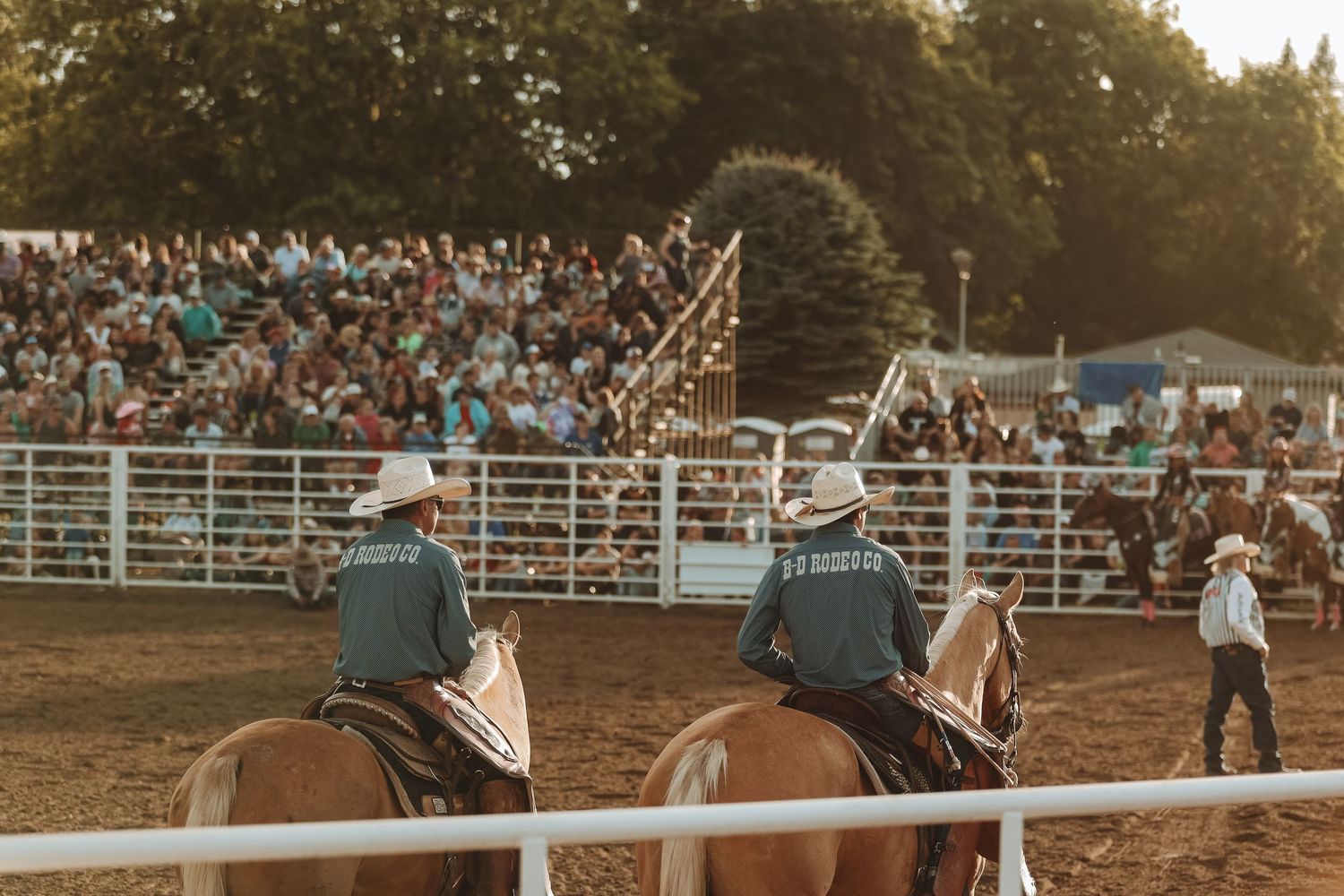 Mounted officials observing the rodeo action from inside the arena.