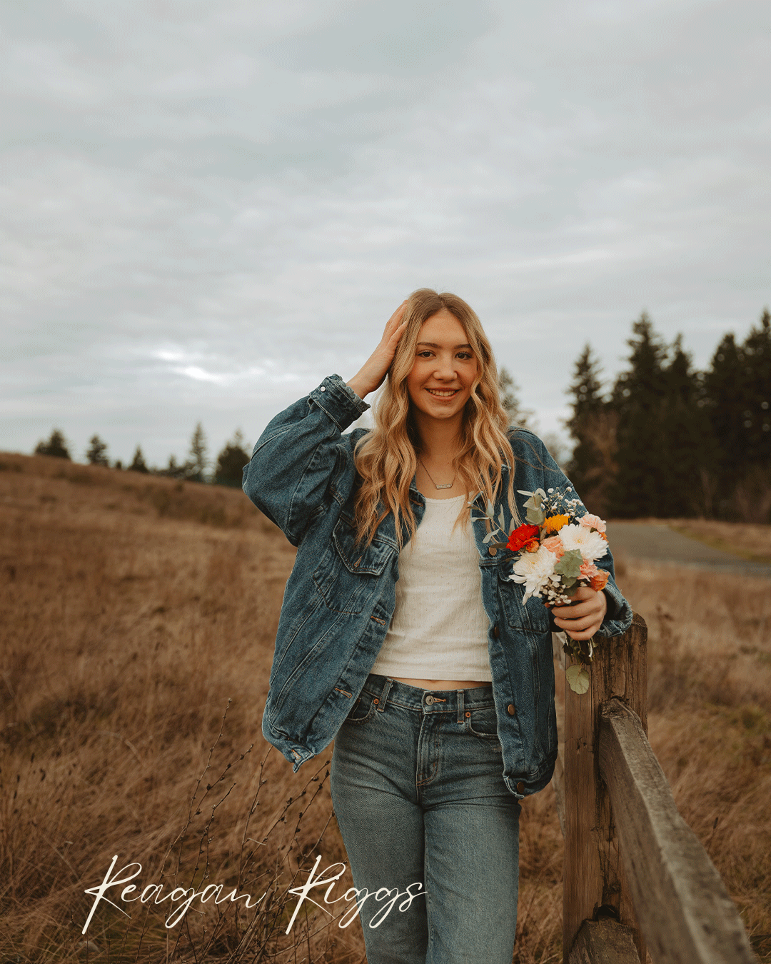 Someone in double denim poses casually in a rustic outdoor setting during golden hour.