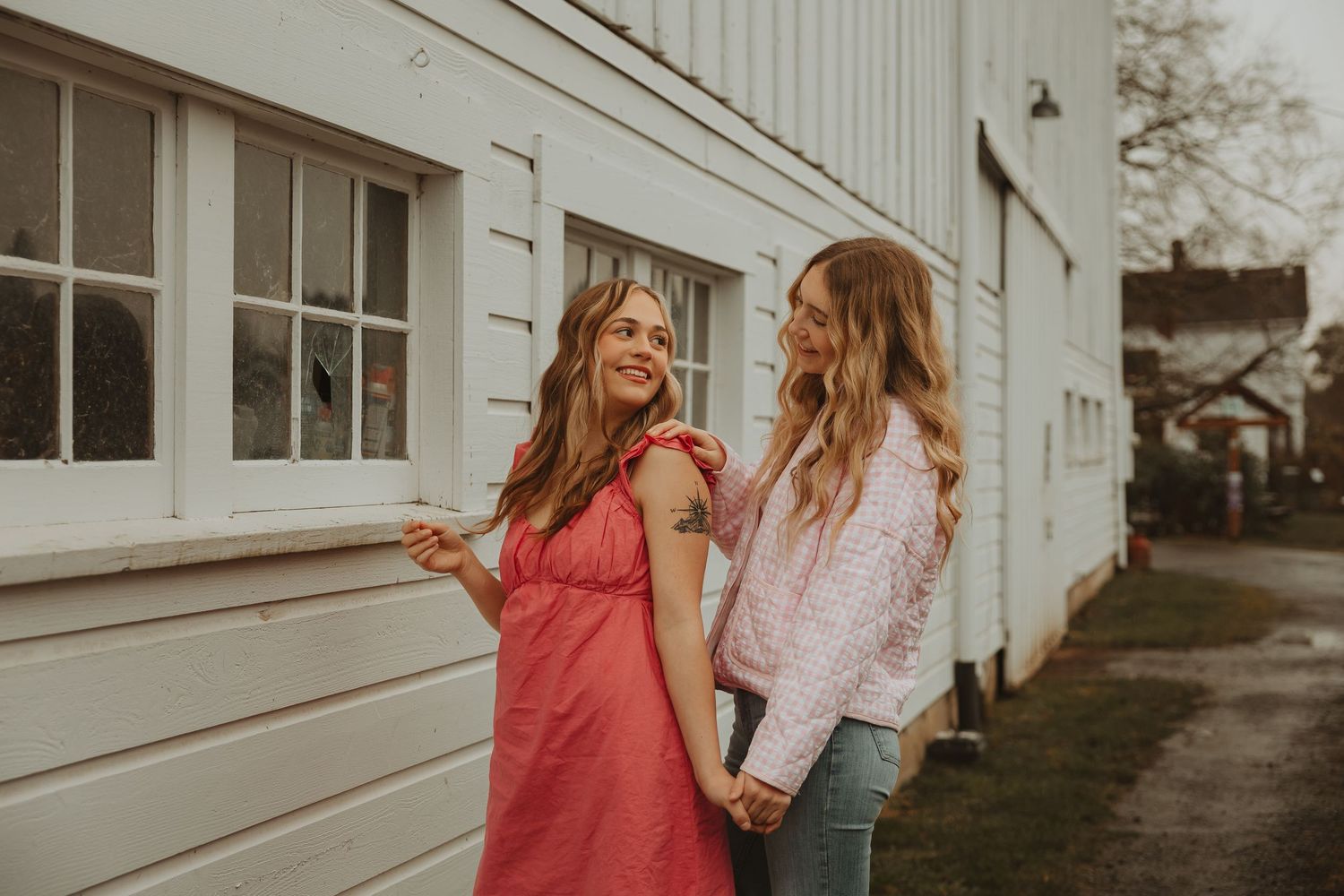Friends enjoying a candid moment outside white building in casual summer outfits.