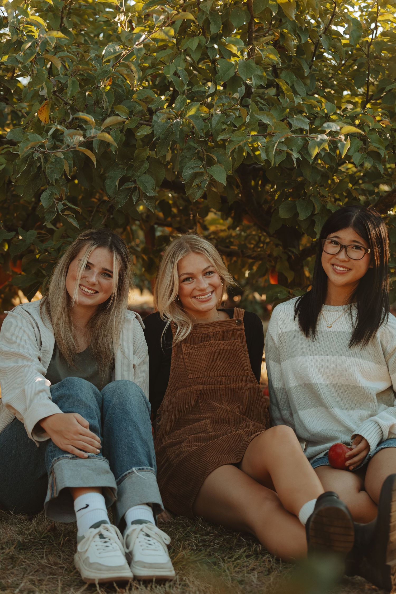 Friends lounging together under trees wearing casual clothes and sneakers.