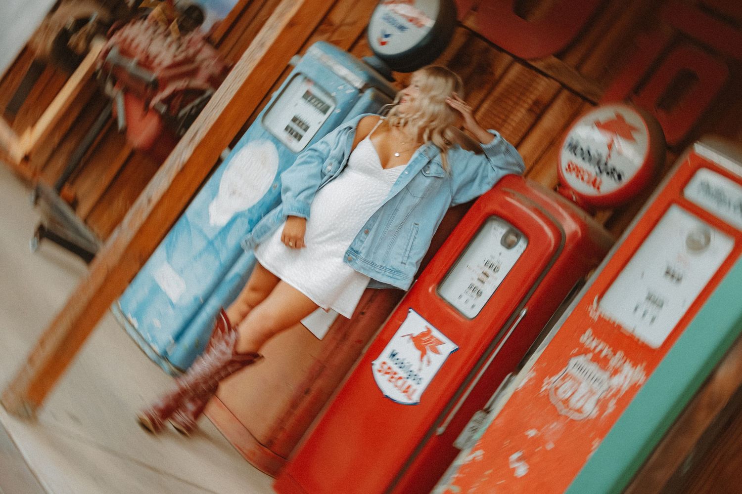 Fashion photo with vintage gas pumps featuring denim jacket and white dress styling.