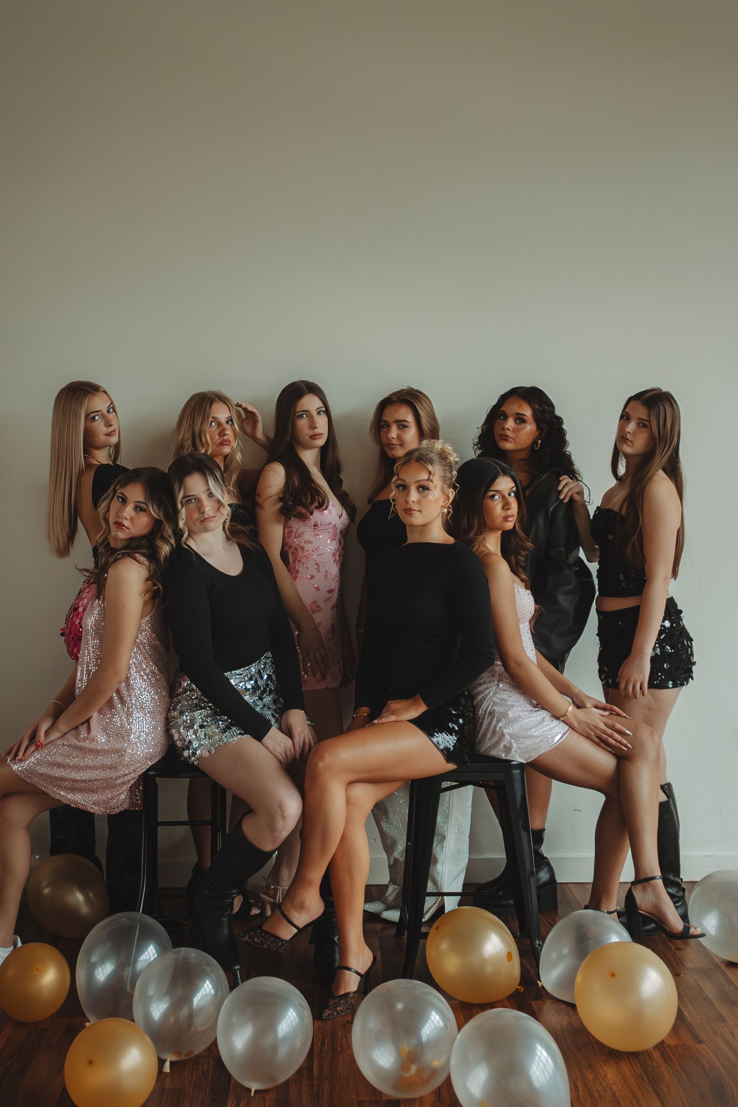 Group photo session with gold and silver balloons arranged on wooden floor against white wall.