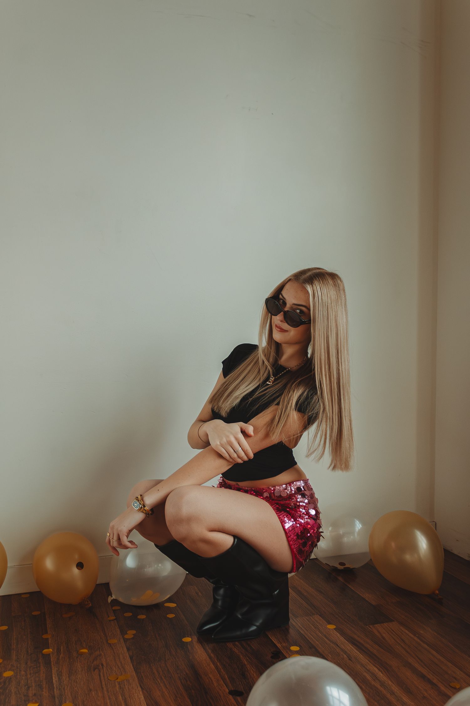 Artistic photo series showing person in black outfit and boots posing against wooden floor with balloons.