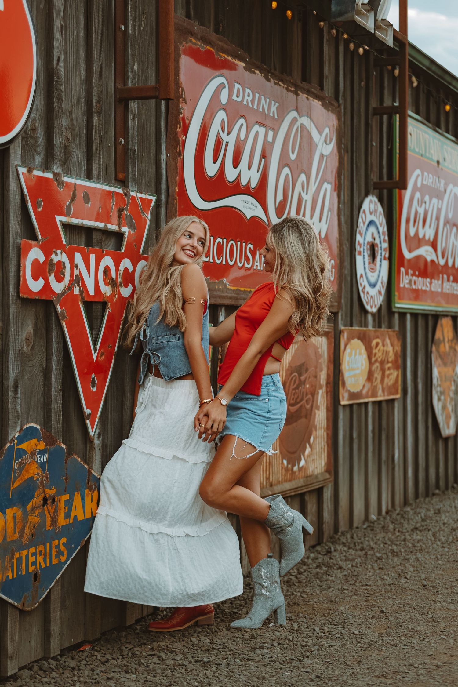 Vintage Coca-Cola signs and advertisements decorate a rustic wooden wall in a retro-themed photoshoot setting.