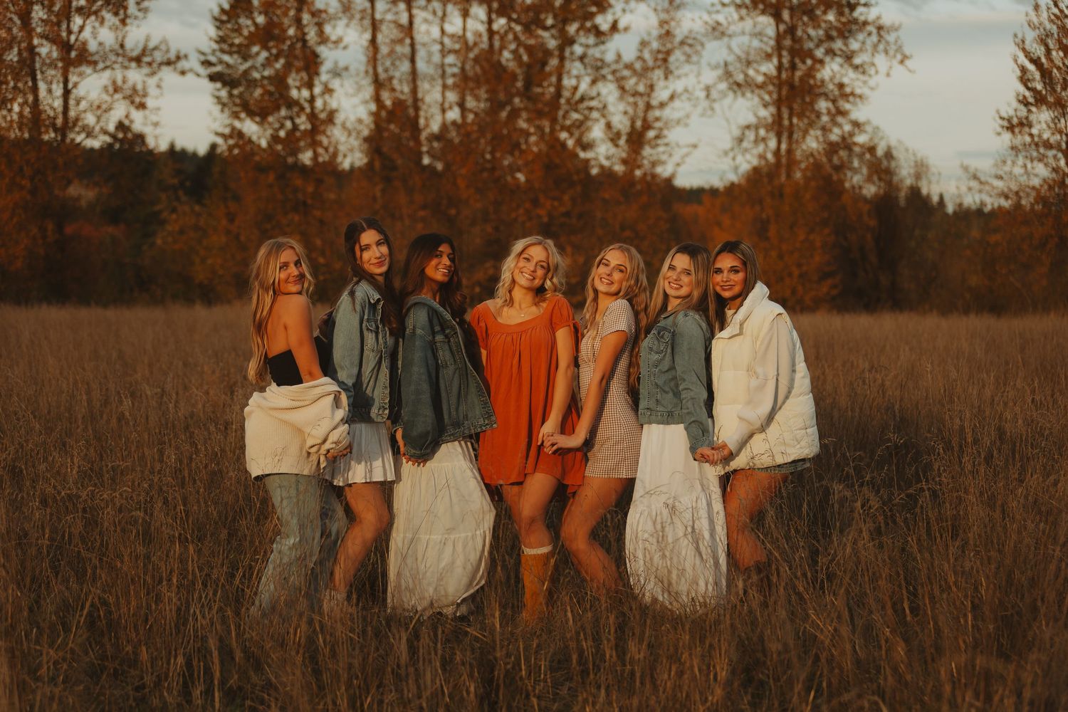 A group of people walking through a golden autumn field at sunset creating a warm nostalgic scene.