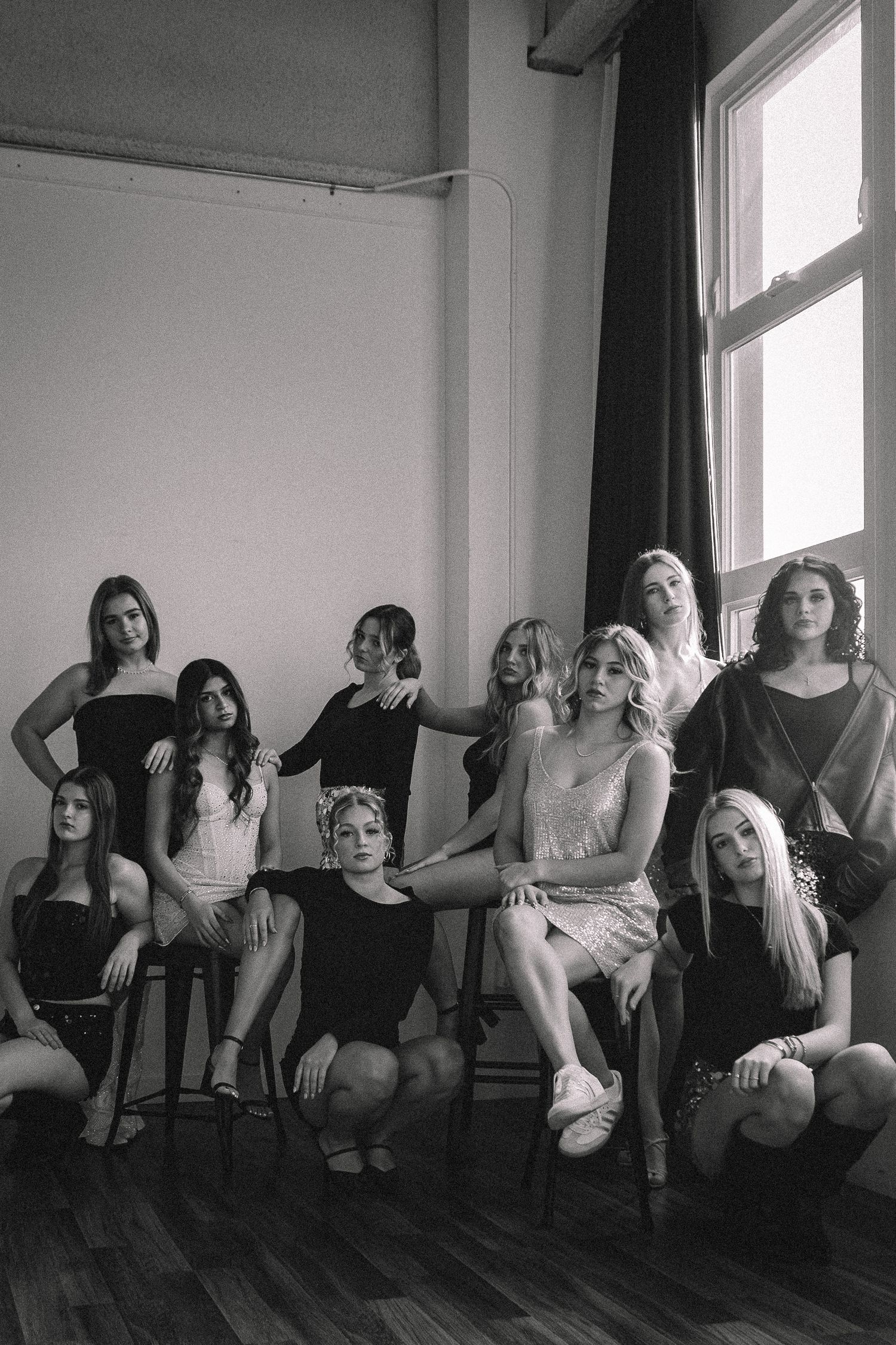 Group of friends lounging together in black and white photo against a bright window.