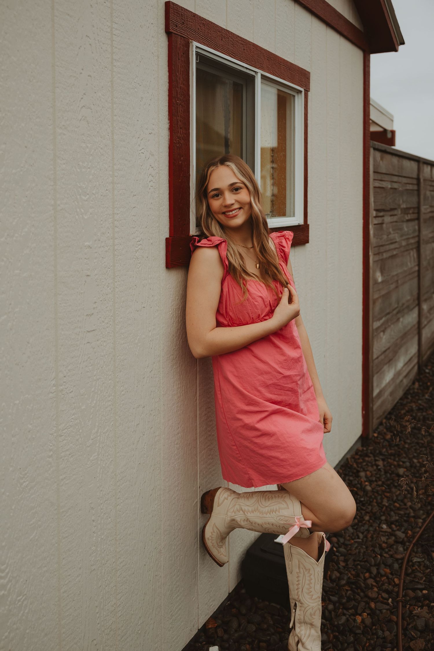 Summer fashion shoot featuring pink tops and cream boots against white building exterior.