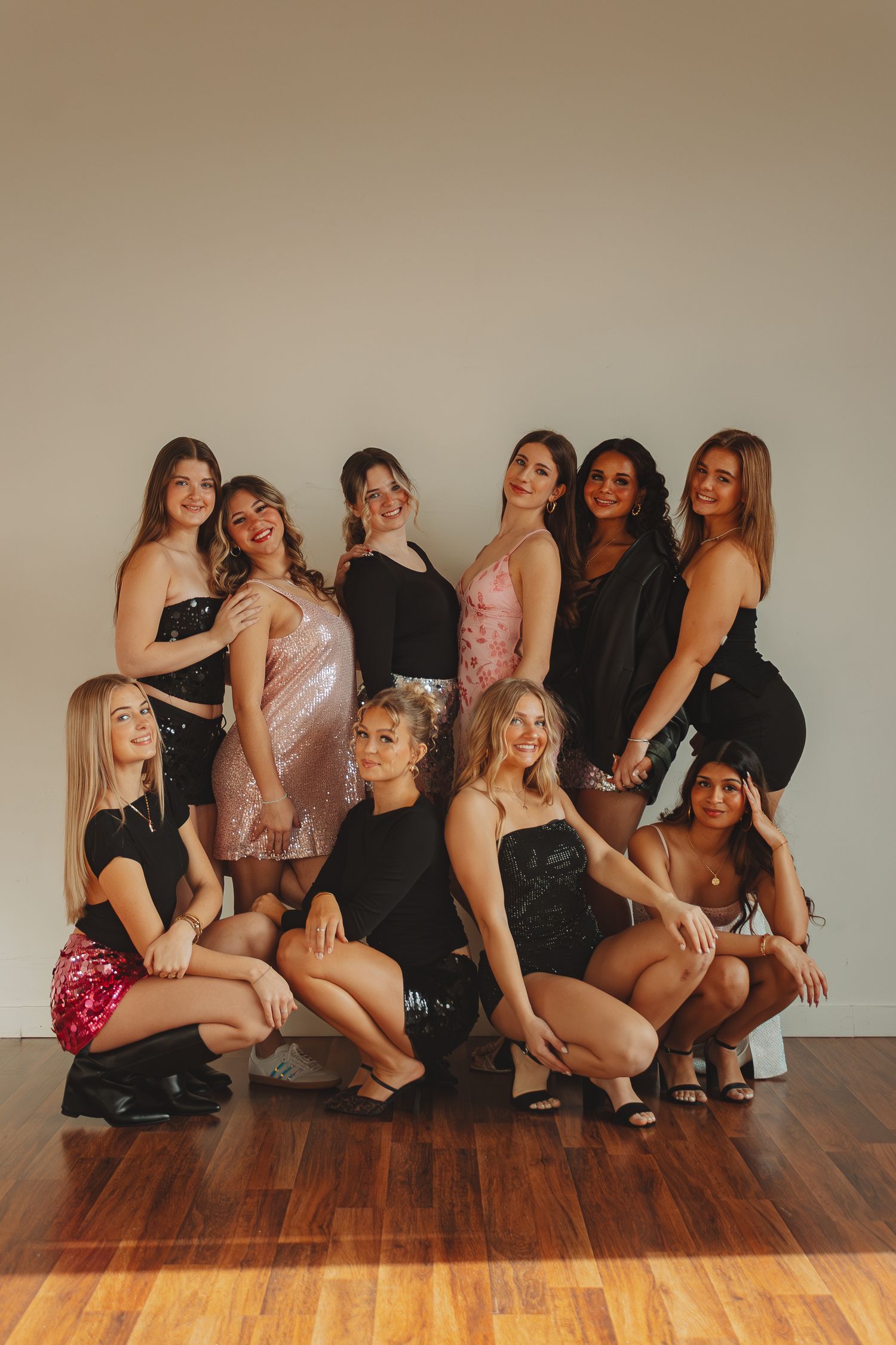 Group photo shoot featuring models in coordinated outfits posing together on wooden floor.