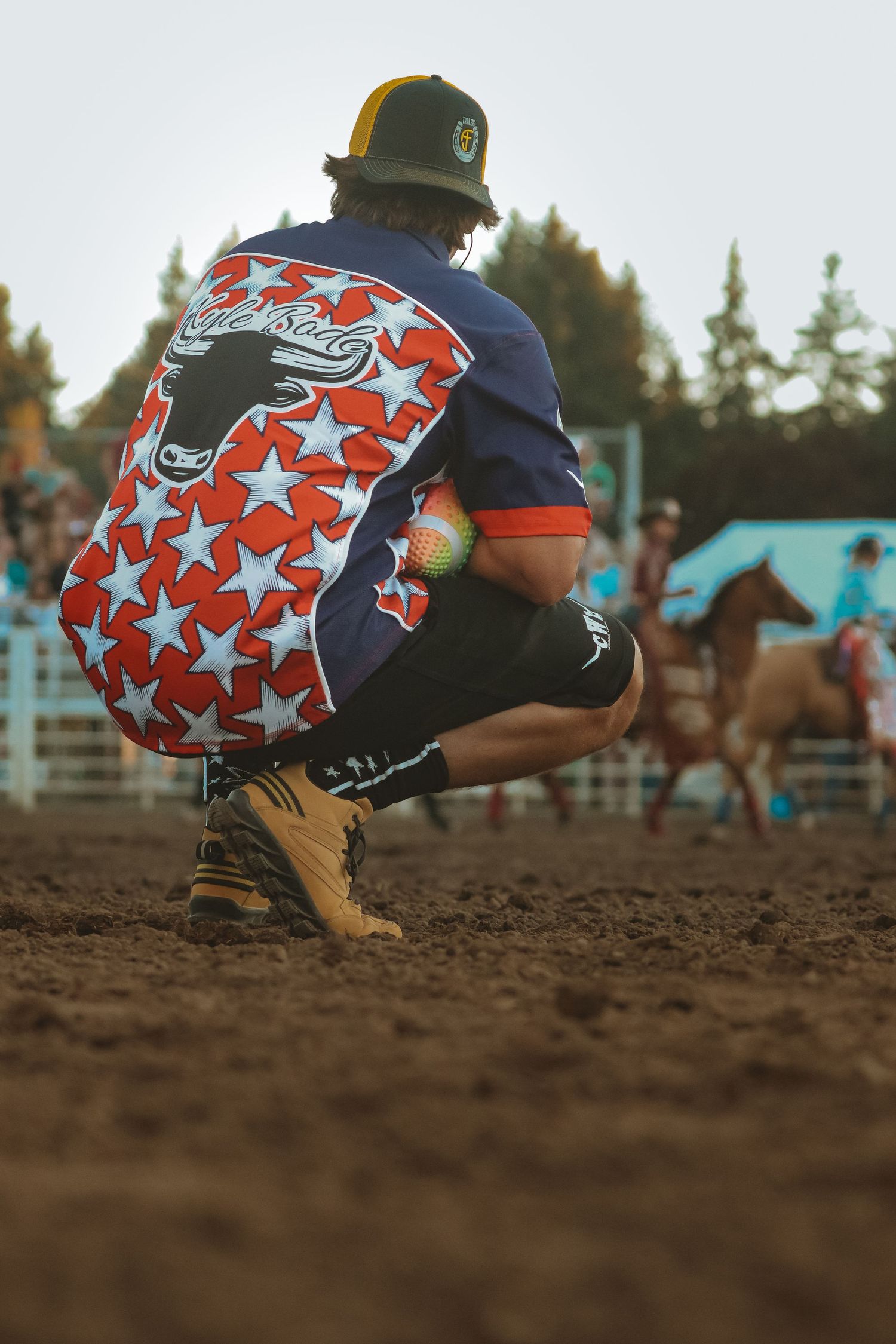 Close-up of star-patterned rodeo gear against dirt arena ground.