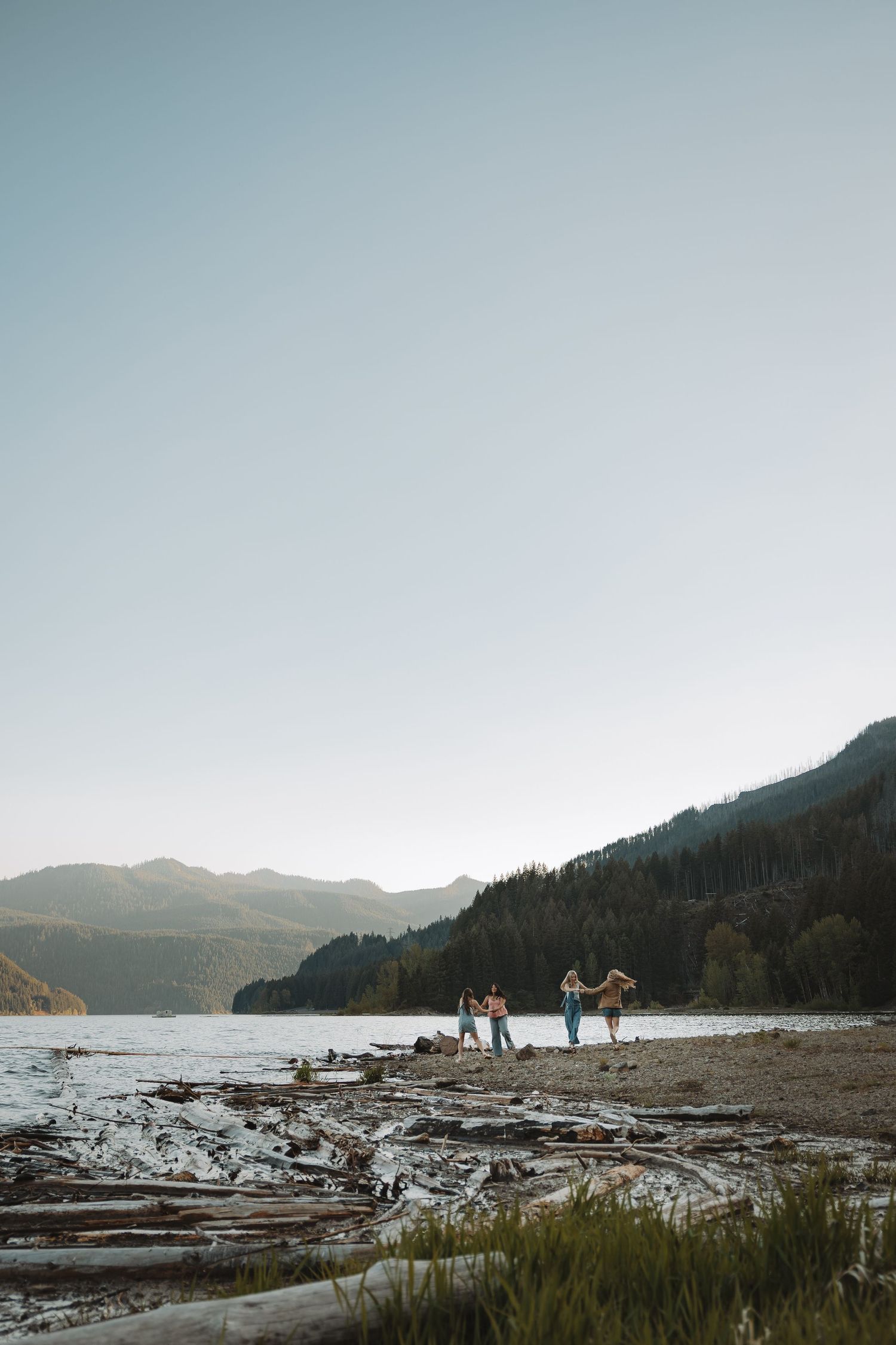 Friends dancing and playing on a scenic mountain lakeside beach at golden hour.