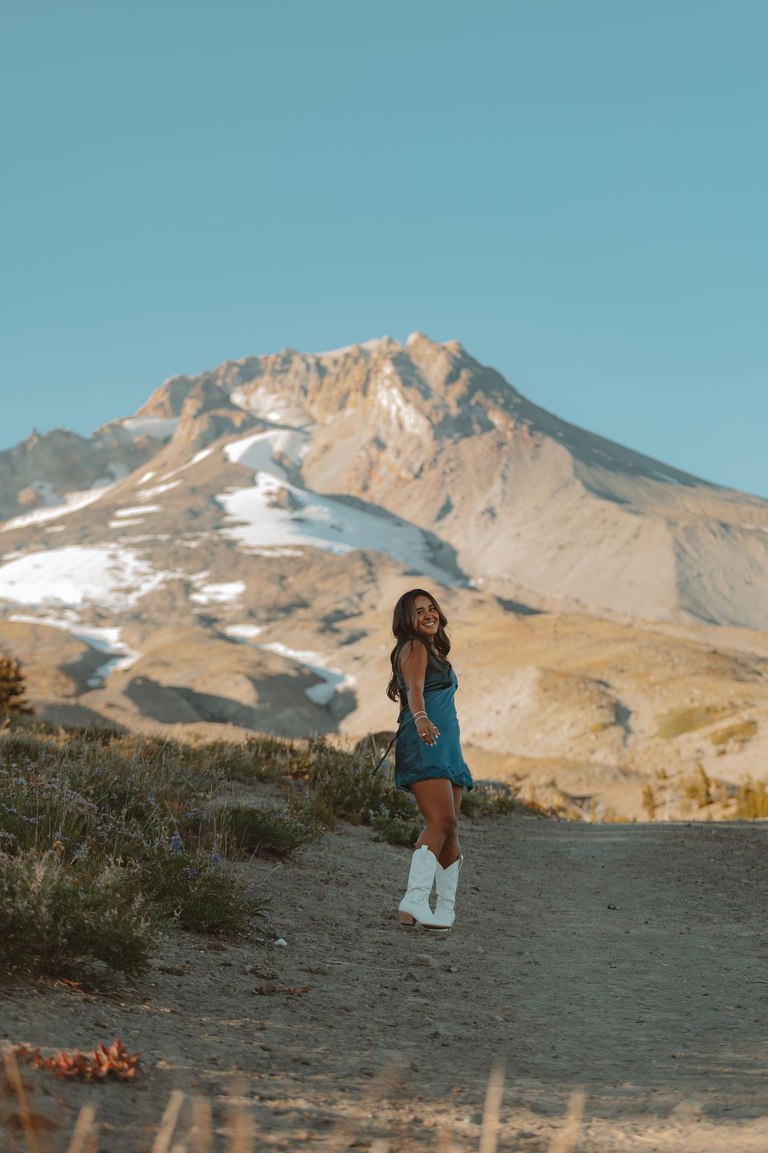 A scenic view of Mount Hood in Oregon with snow patches and rocky terrain against a bright blue sky.