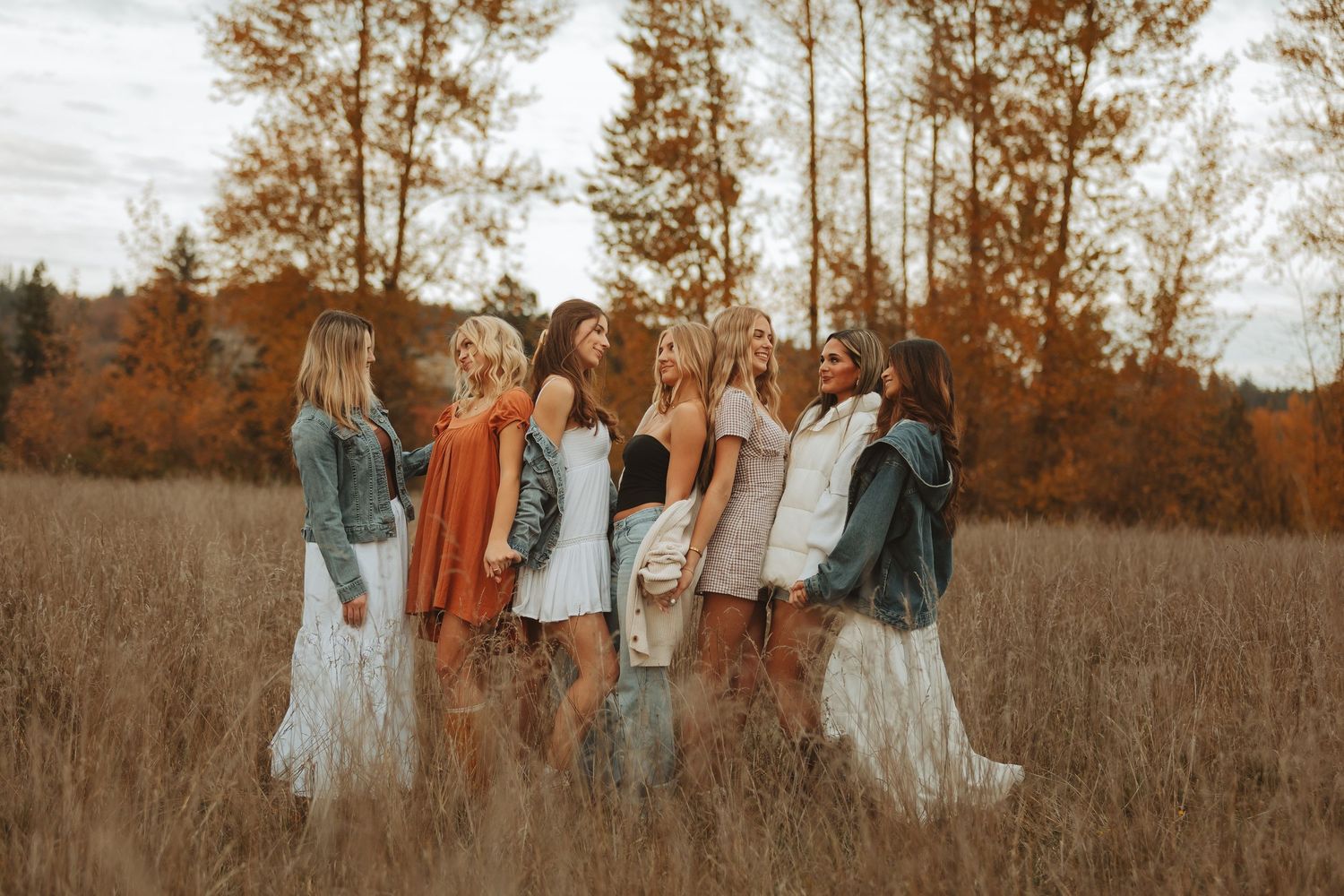 Group photo session in a golden autumn field with matching casual outfits.