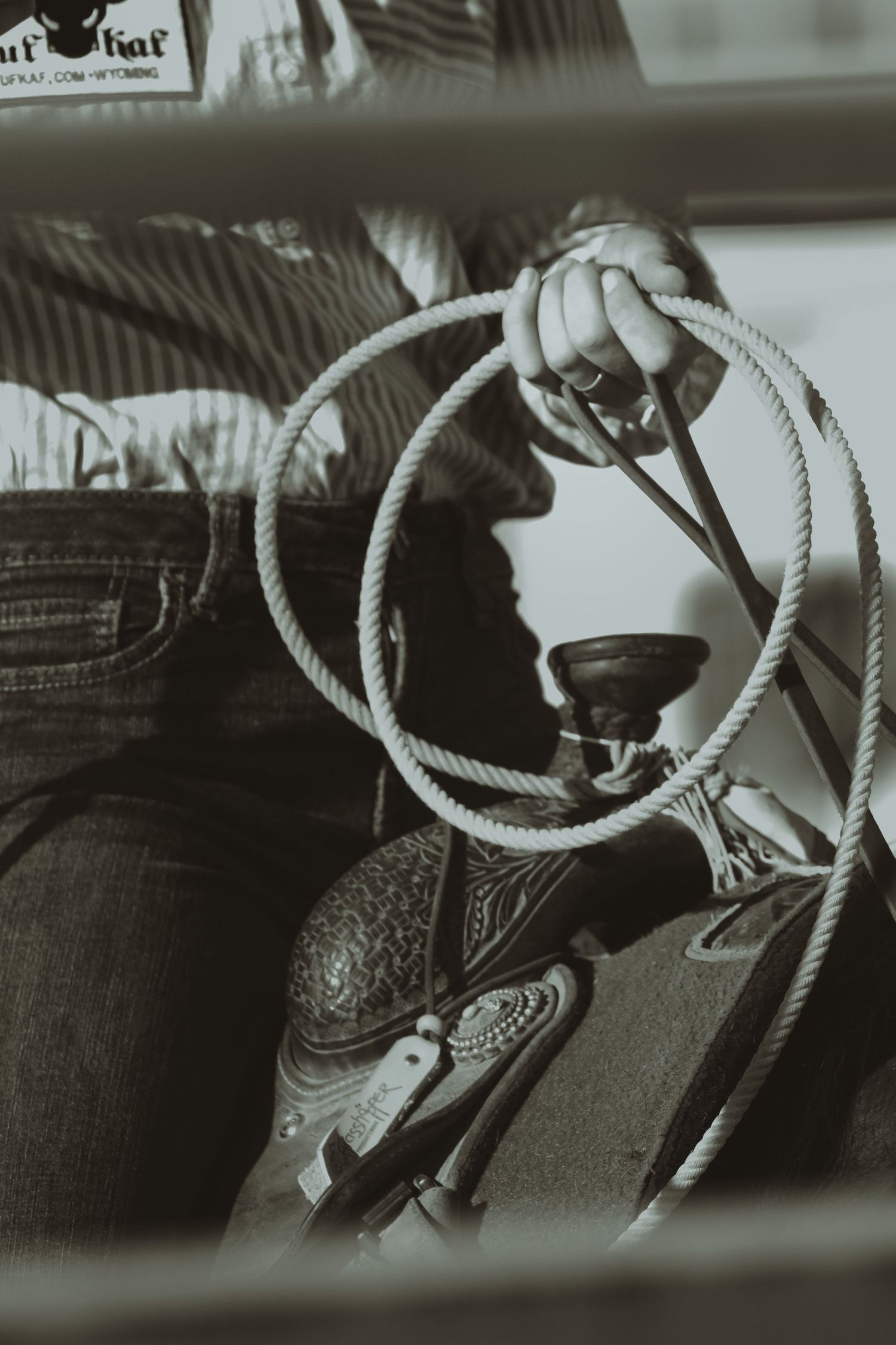 Close-up detail of western boots and rope in black and white.