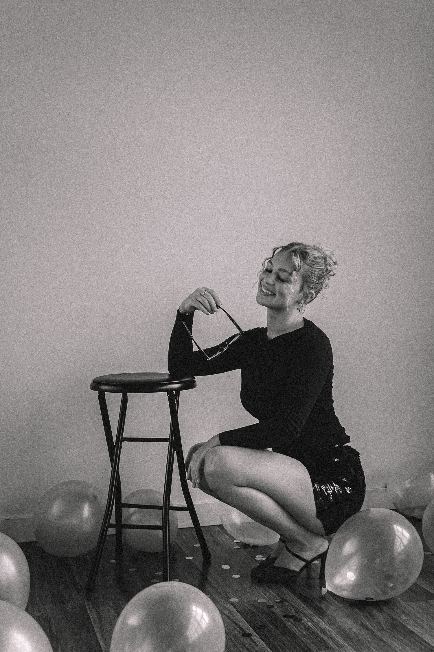 A sequence of black and white photos showing a person in dark clothing lying down with balloons in an artistic composition.