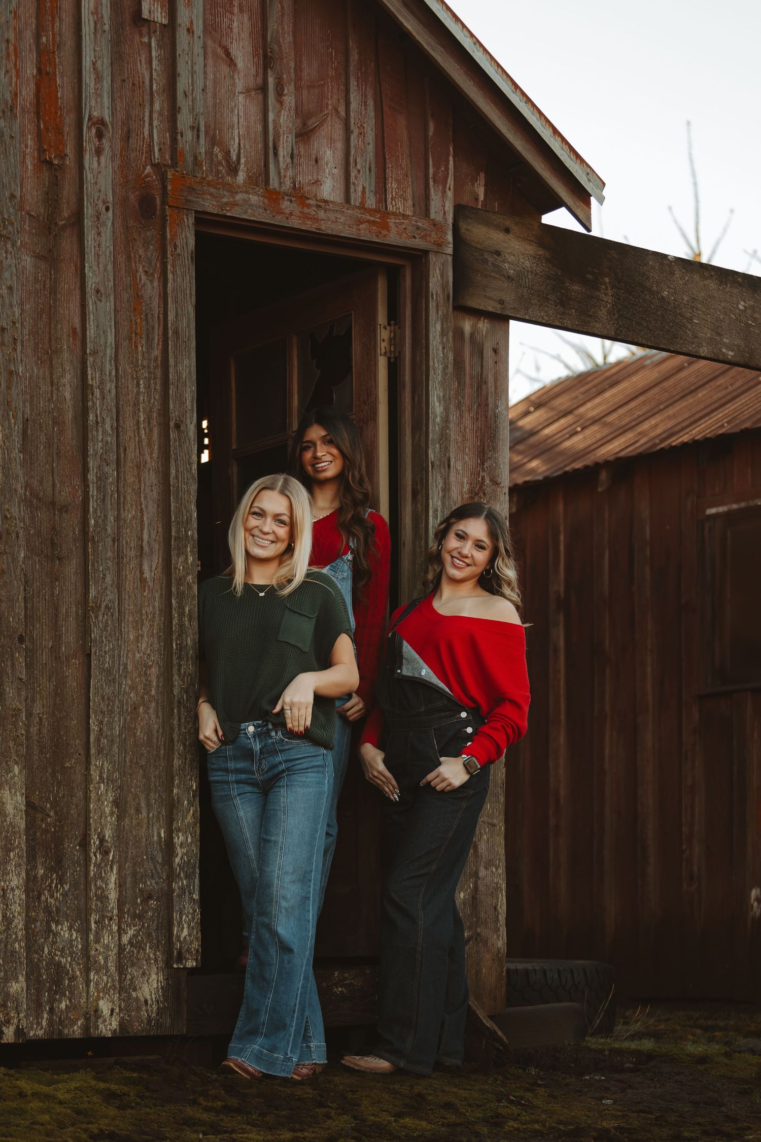 Friends gather for photos by a weathered wooden barn in casual western-inspired outfits.