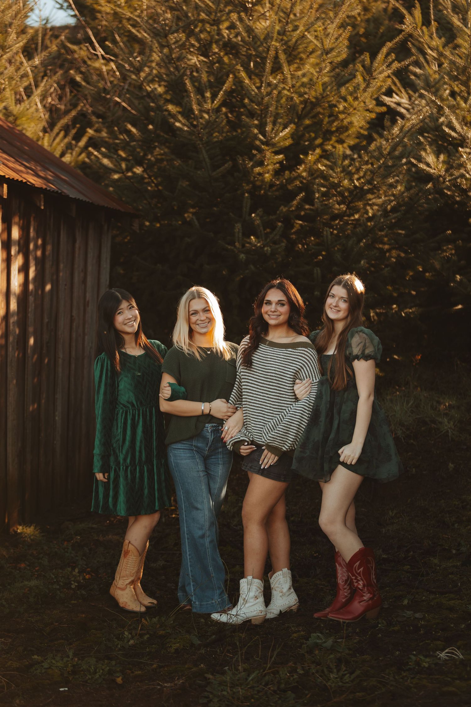 Four friends in casual winter outfits pose together against a wooden barn backdrop.