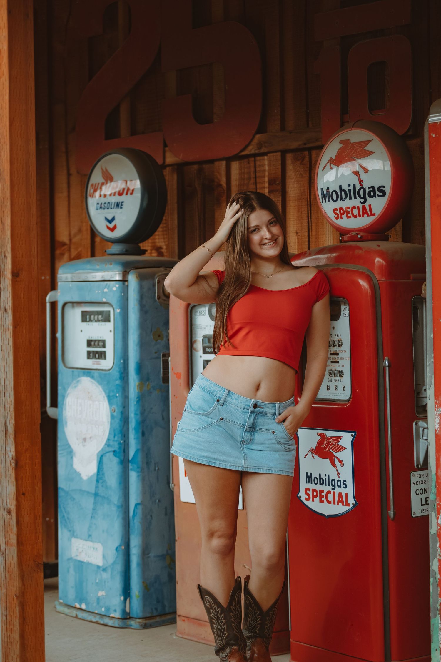 Vintage gas pumps and Mobilgas signs line a rustic wooden wall in red and blue tones.