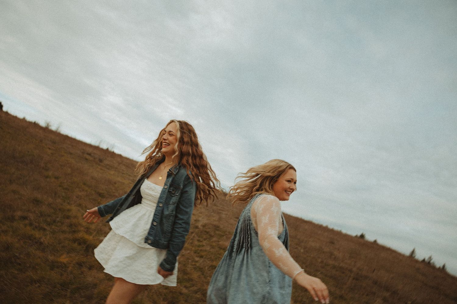 Dancing figures in light colored tops move freely against a moody autumn hillside backdrop.