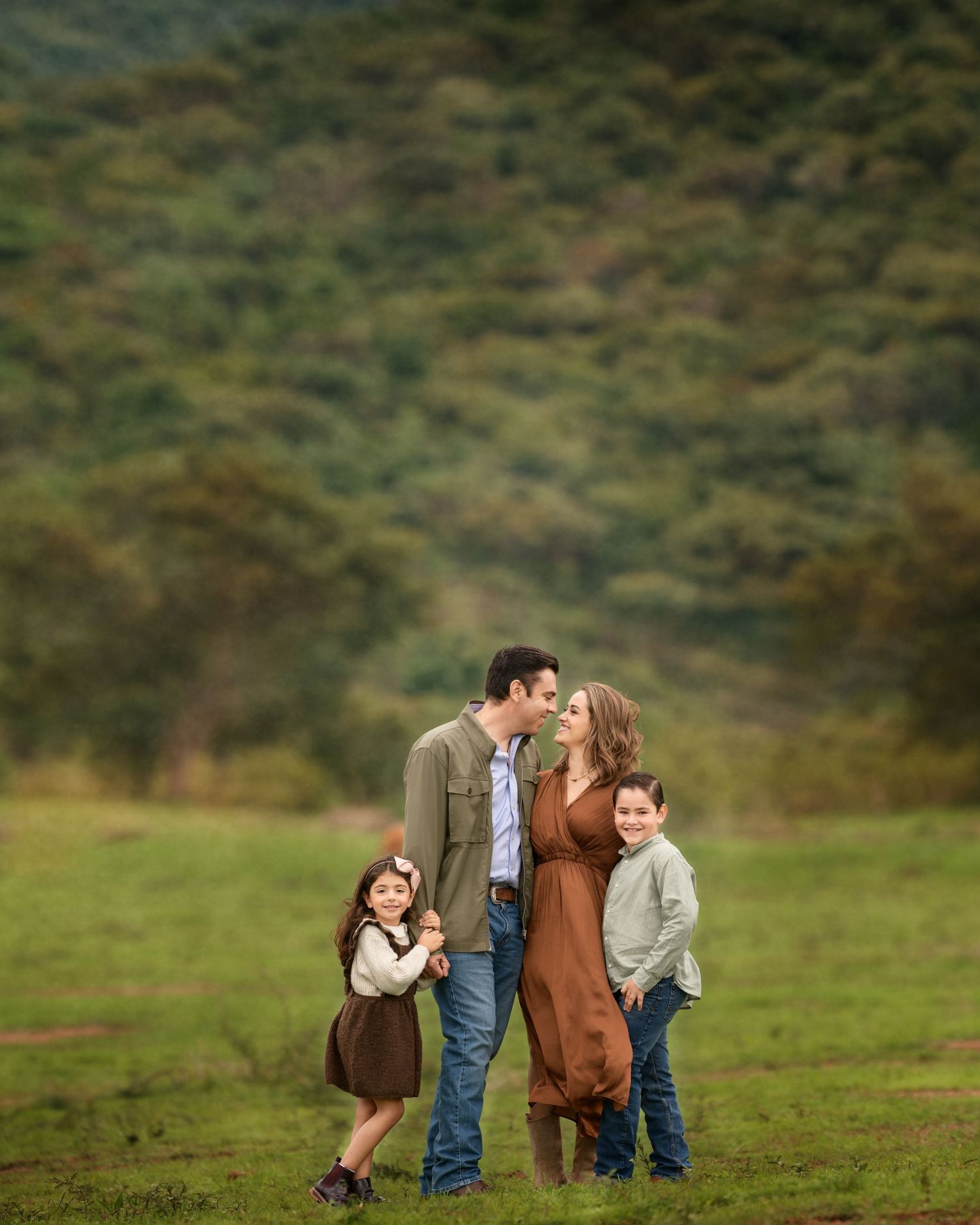 A loving family enjoying a tender moment together in a lush green field.
