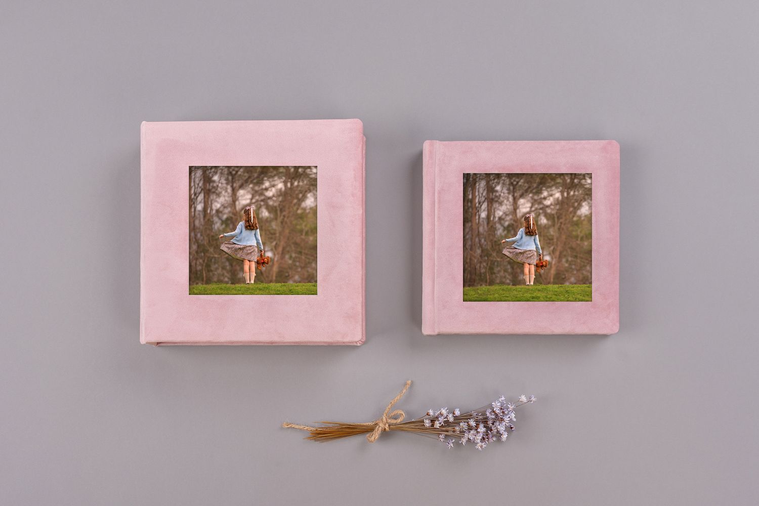 Two pink photo frames of little girl displayed on gray wall with dried botanical accent.