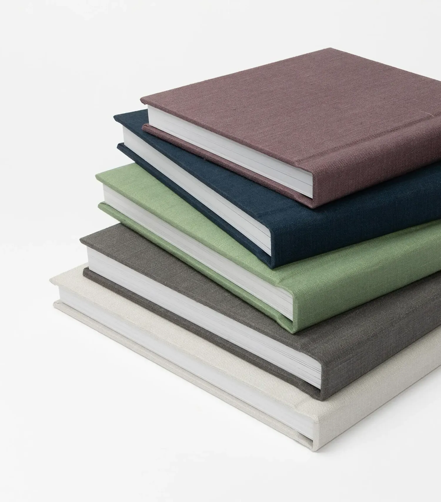 Stack of hardcover photo albums in muted tones of burgundy, navy, sage green, and gray.