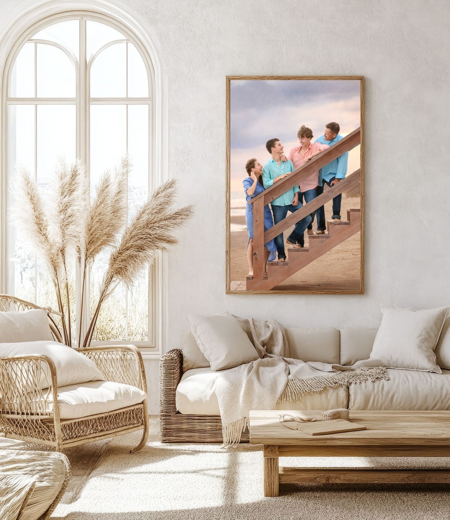 A modern boho living room with neutral tones, pampas grass decor, and framed beach photos displayed on white walls.