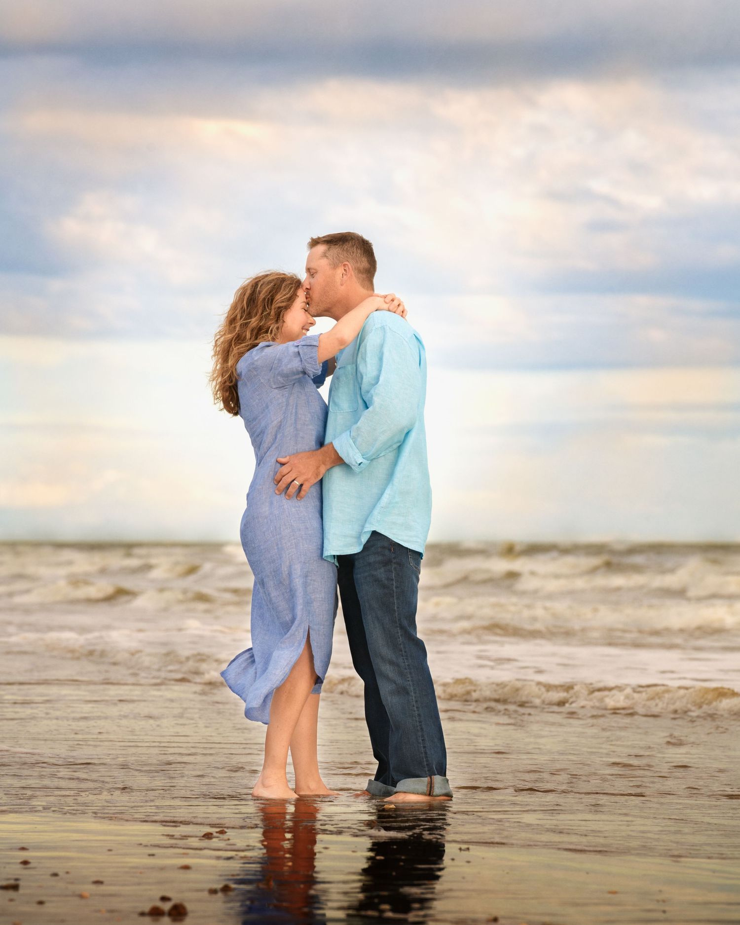 Intimate beachside moment between couple during golden hour with ocean waves.