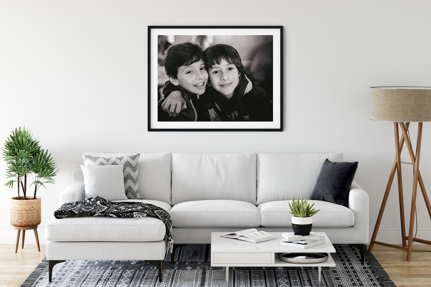 Black and white framed photograph of boys displayed above a modern gray sectional sofa with decorative pillows.