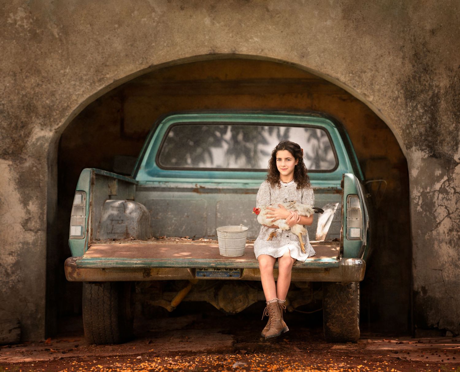 Artistic portrait in sepia tones featuring a vintage truck tailgate under a stone arch.