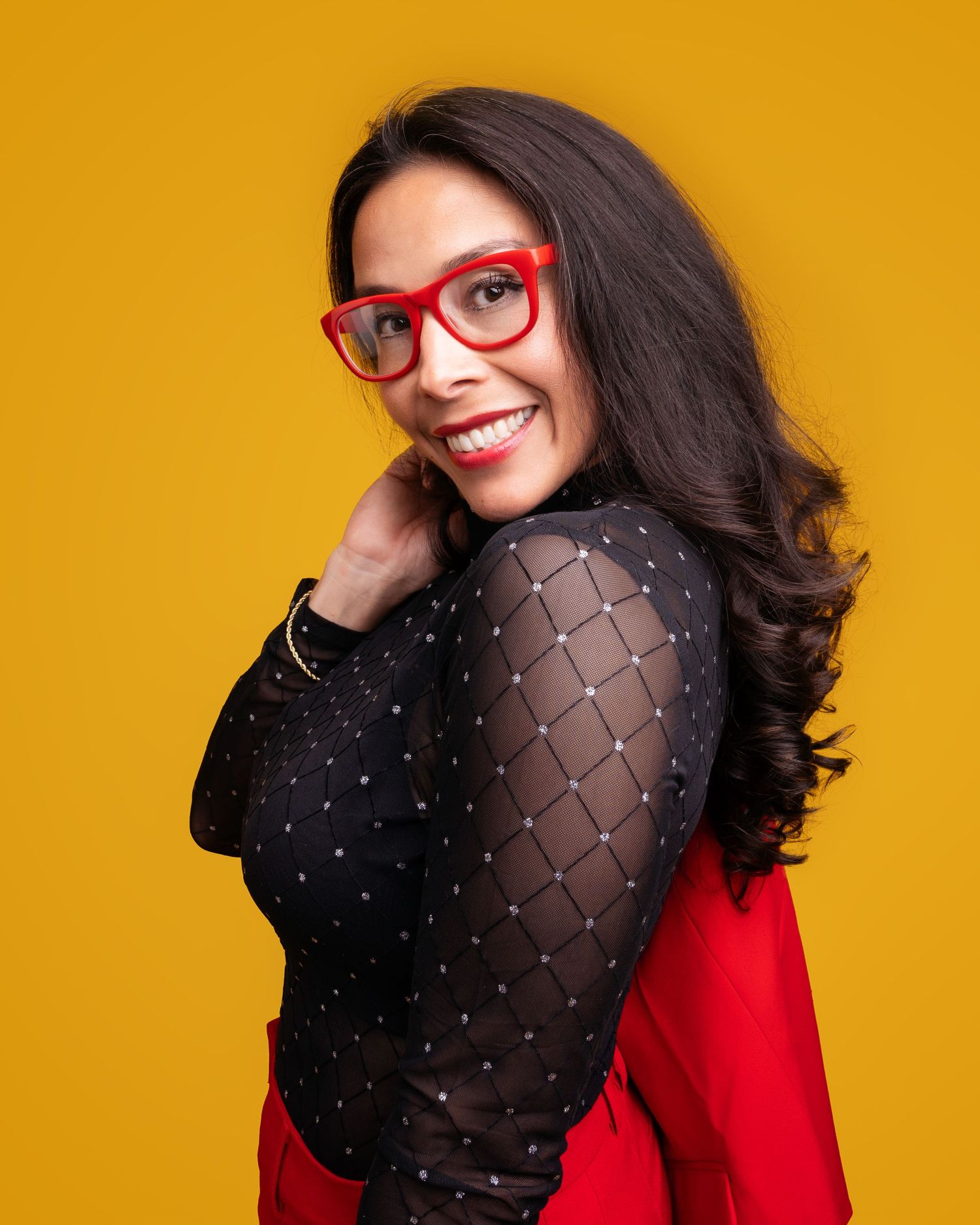 Glamorous red and black outfit against yellow backdrop in studio portrait.
