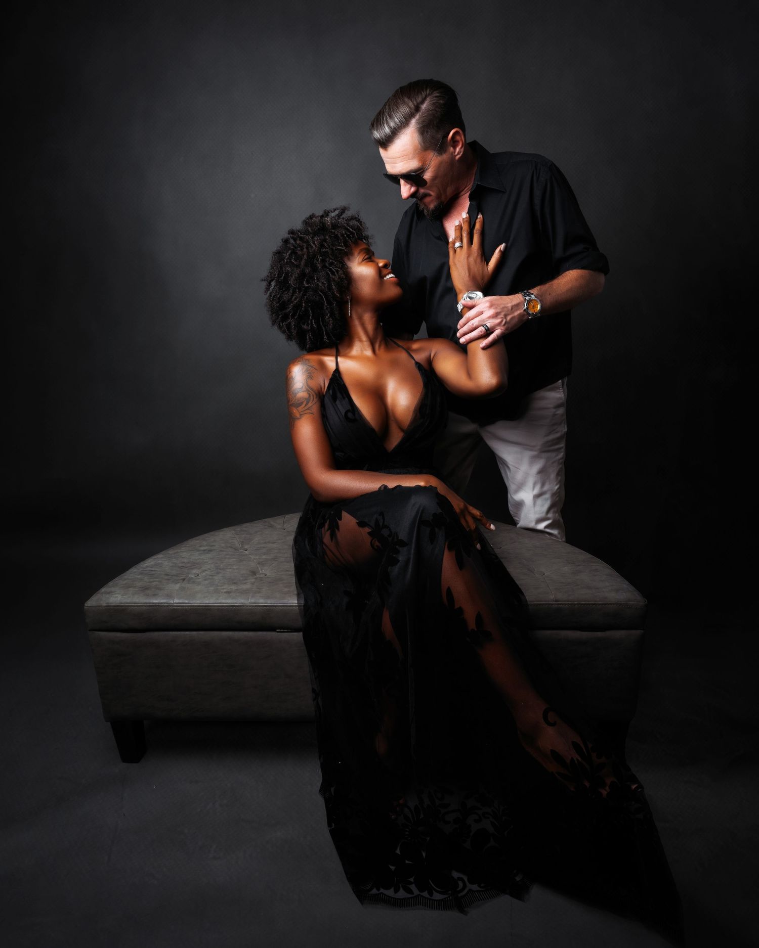 Intimate couple portraits in dark tones showing tender moments on minimalist set.
