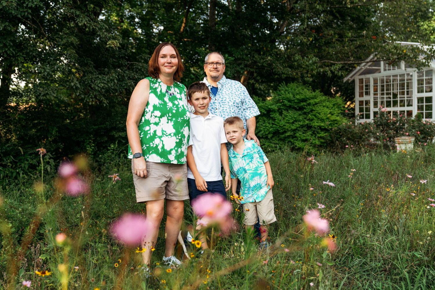 A summer family portrait with coordinating tropical print outfits in a wildflower garden.