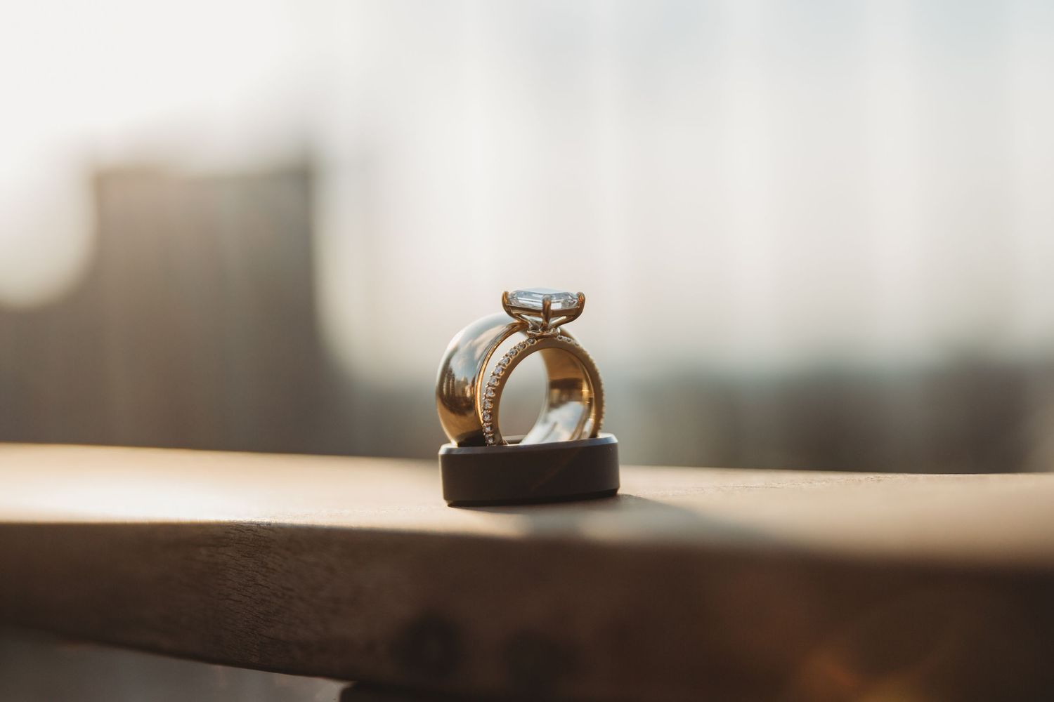 Delicate wedding rings displayed on a blurred wooden surface.