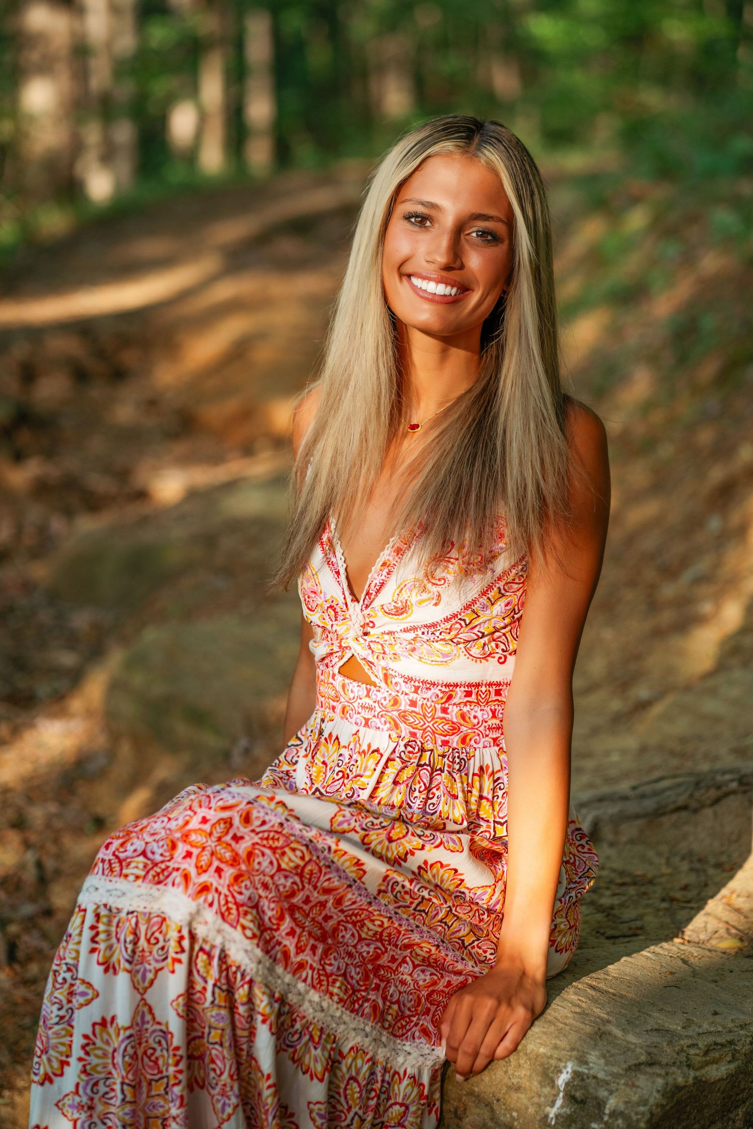 A bohemian summer portrait featuring a floral maxi dress on a forest trail.