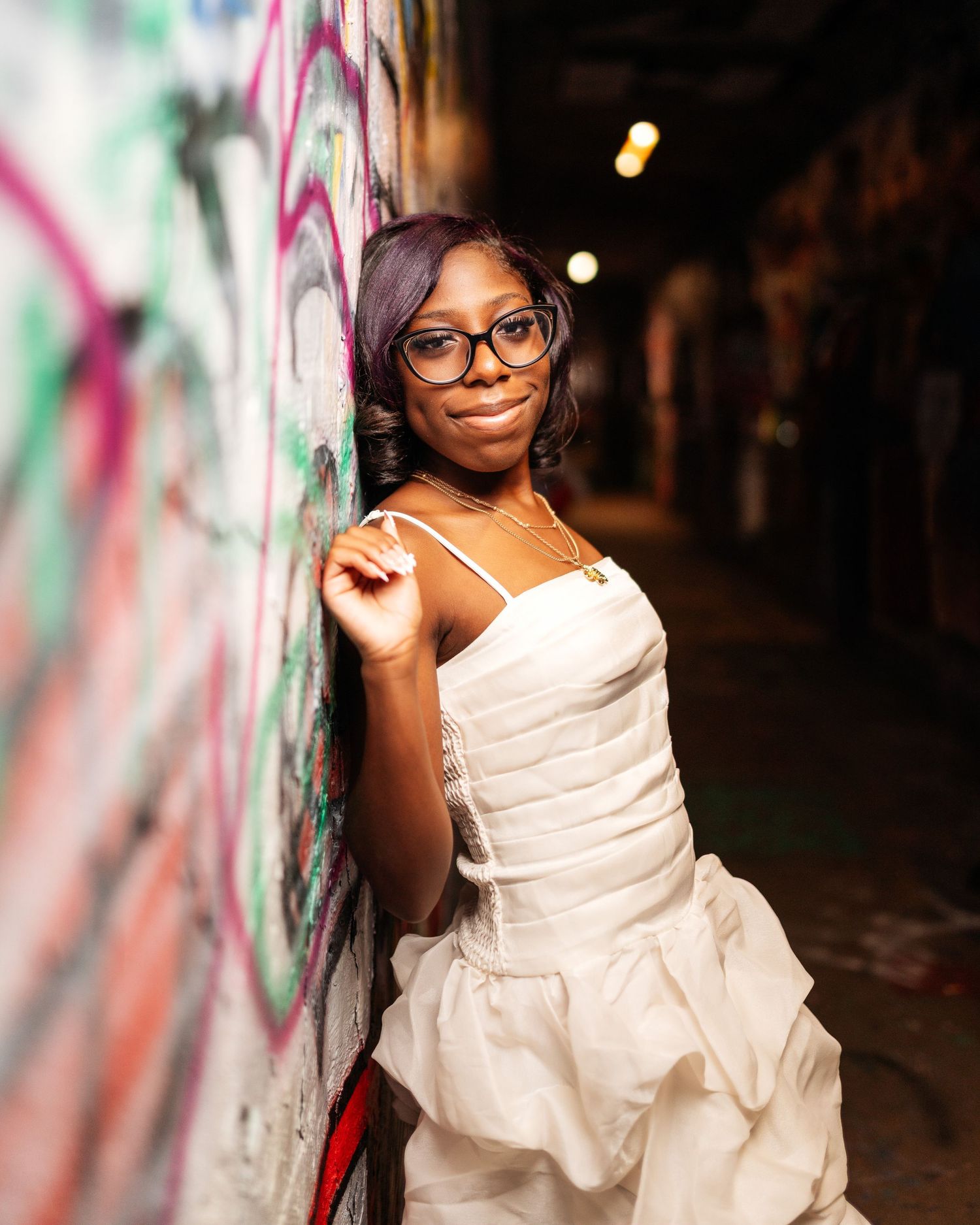 Artistic portrait against graffiti wall featuring white formal dress.